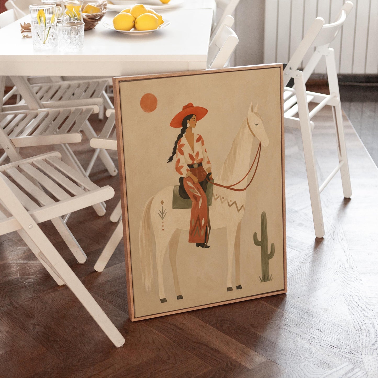 Cowgirl in a red hat sitting on a white horse beside a cactus in warm sand, canvas wall art seen in a warm interior with natural light