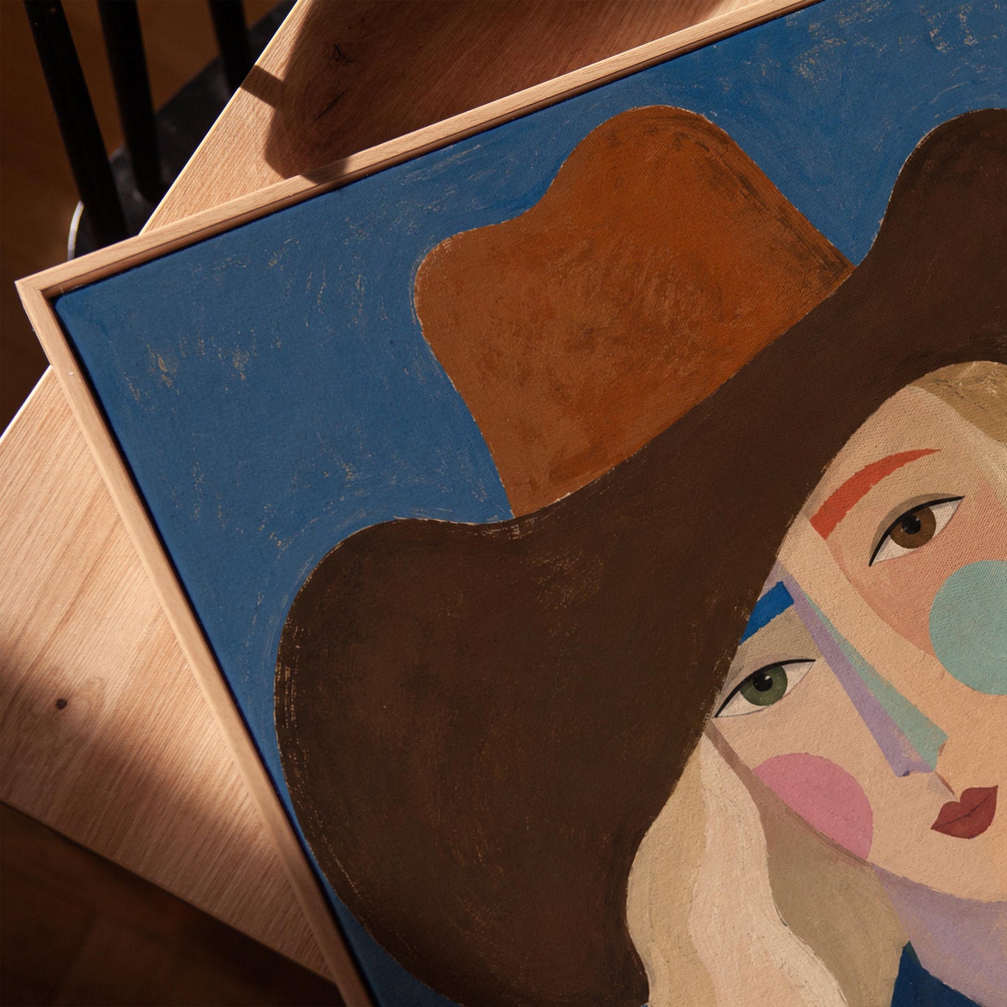 Blonde cowgirl in a rust hat with a cubist pastel face on deep blue, canvas print in a warm, minimally styled interior