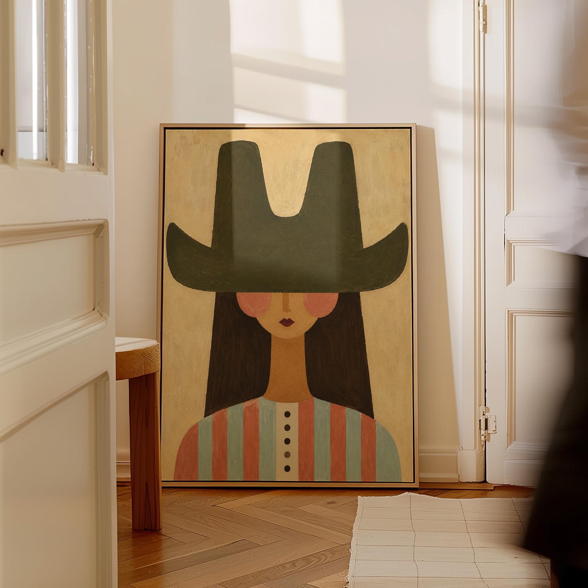 Folk cowgirl in a big green hat and striped shirt with long dark hair, canvas wall art hanging in a calm, modern living space