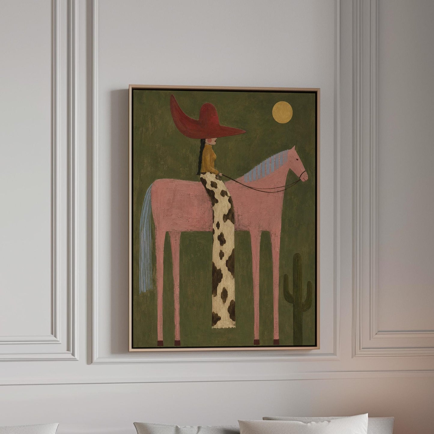 Cowgirl in a red hat riding a tall pink horse past a cactus under the moon, canvas print in a bright room with natural daylight