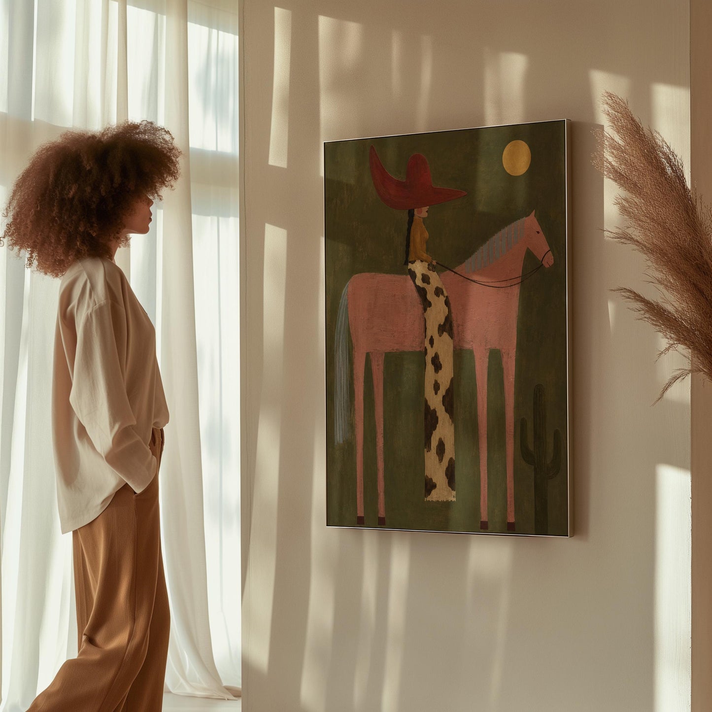 Cowgirl in a red hat riding a tall pink horse past a cactus under the moon, canvas print shown to scale in a furnished room
