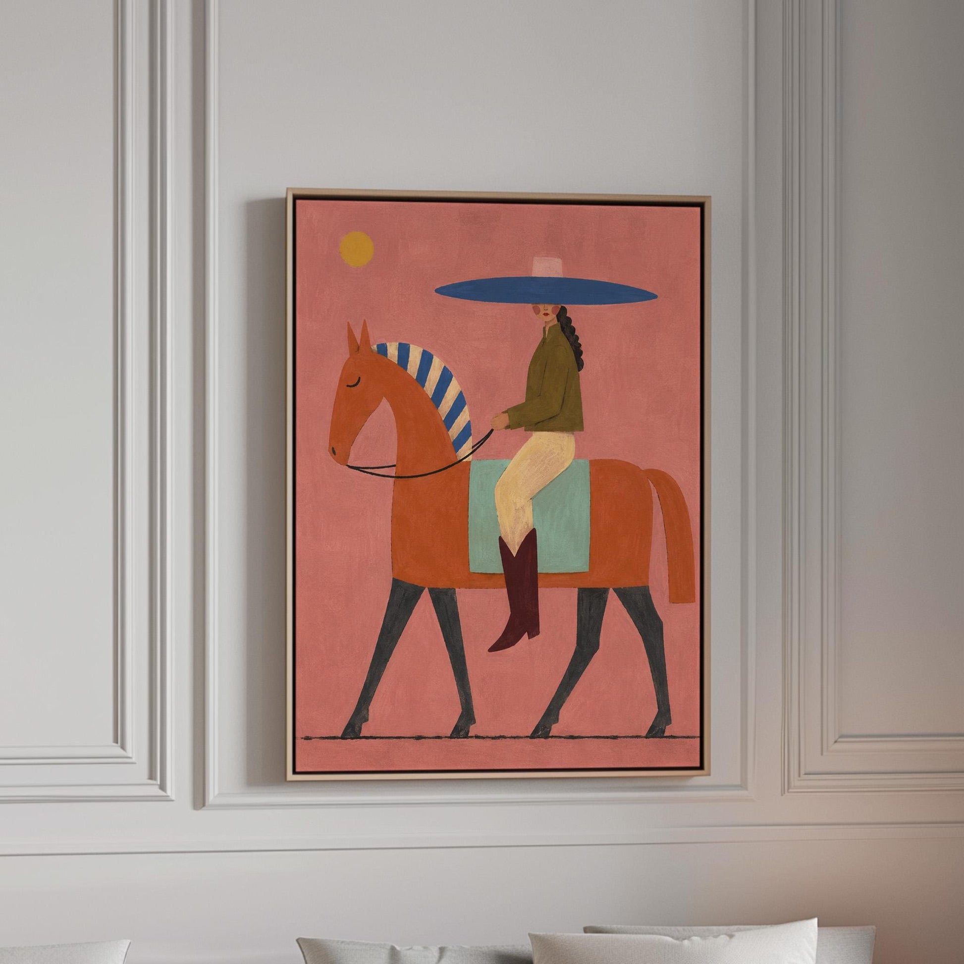 Cowgirl in a broad blue hat riding a rust red horse across a coral sky, canvas print in a bright room with natural daylight