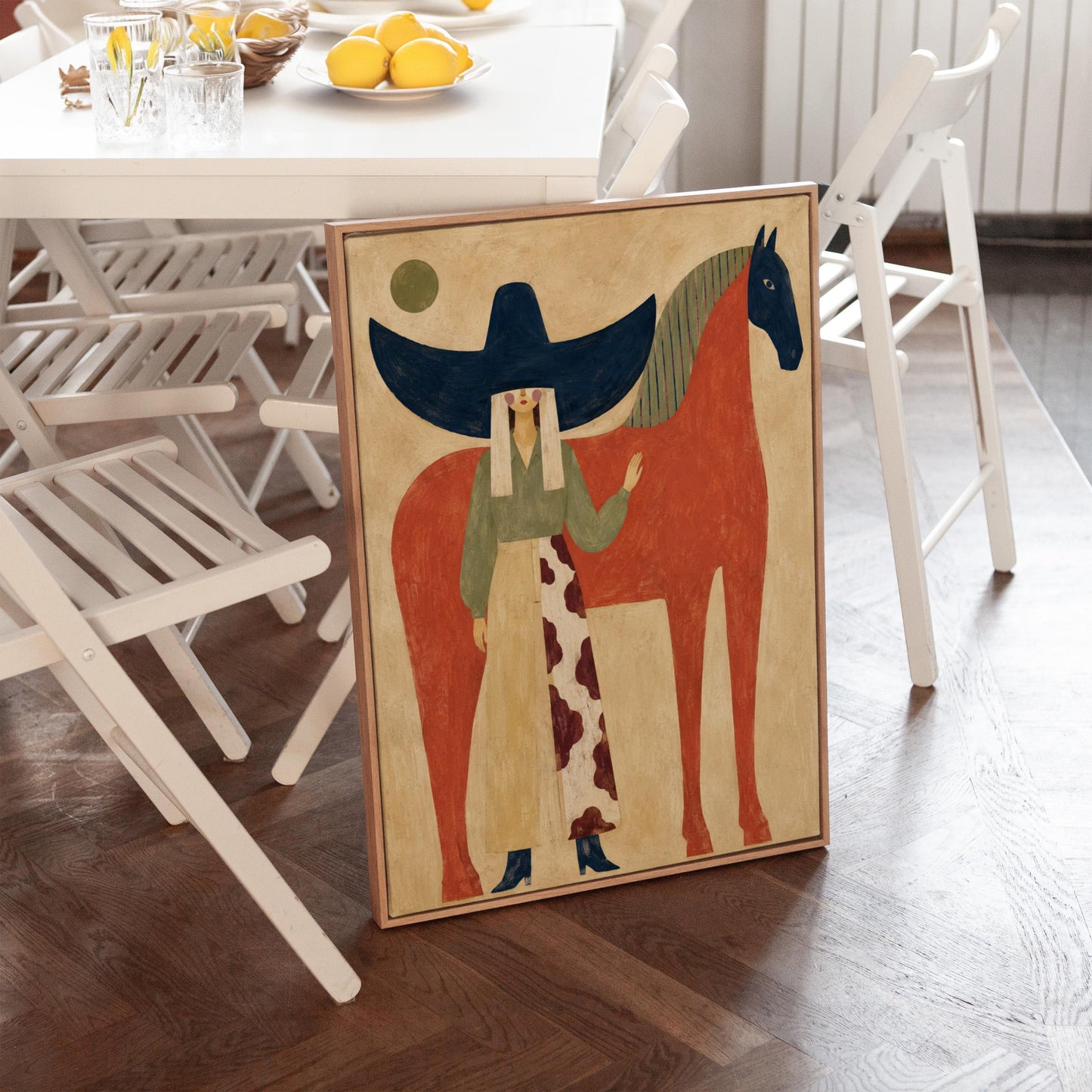 Woman in a navy hat standing by a red horse with a dark head under a moon, canvas print seen in a warm interior with natural light