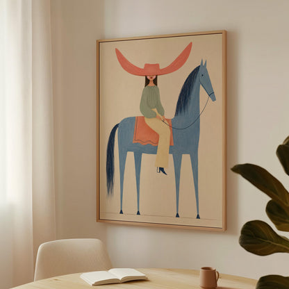 Cowgirl in a dramatic red hat riding a slender blue horse across pale sand, canvas print on a quiet wall in a considered interior