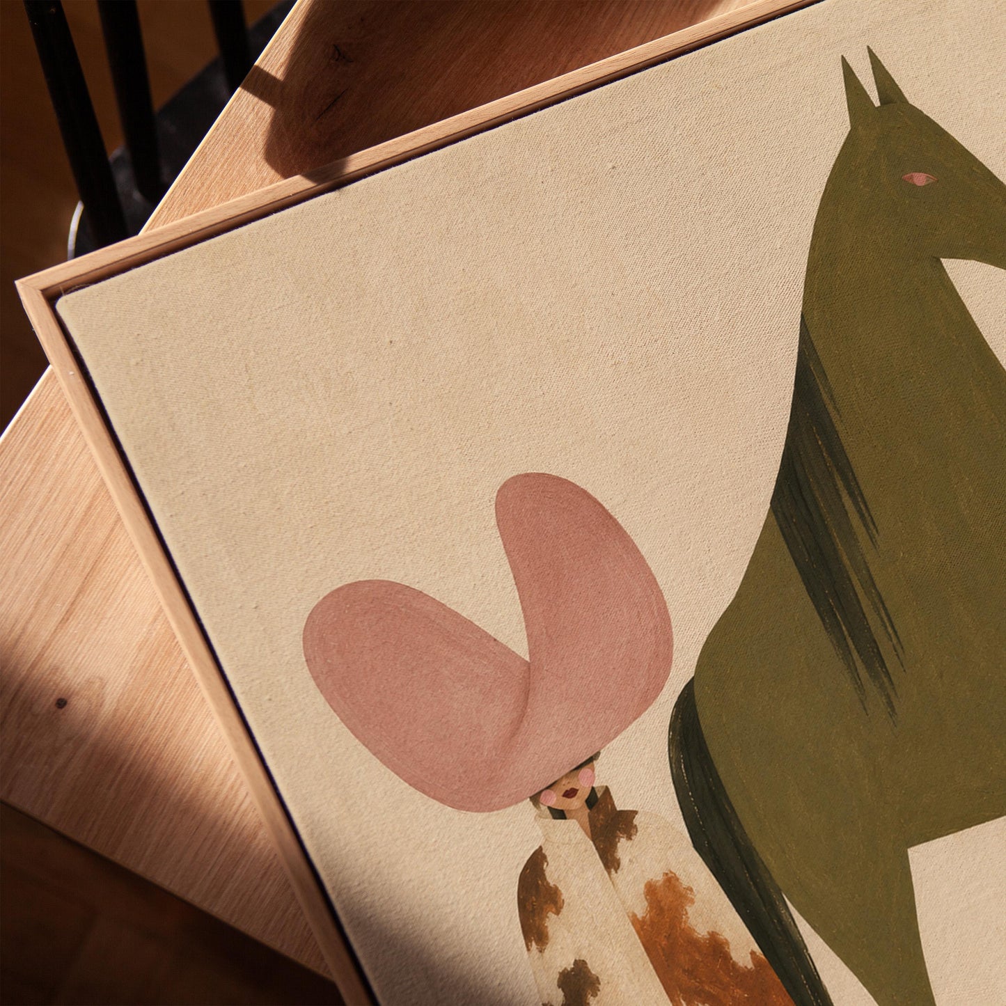 Cowgirl in a green hat and spotted pants before a deep maroon folk horse, canvas print in a warm, minimally styled interior