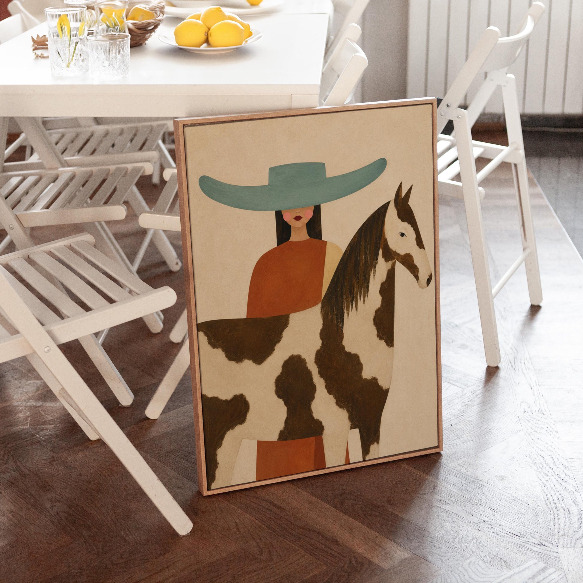 Woman in a teal hat beside a brown and white pinto horse in warm light, canvas print seen in a warm interior with natural light