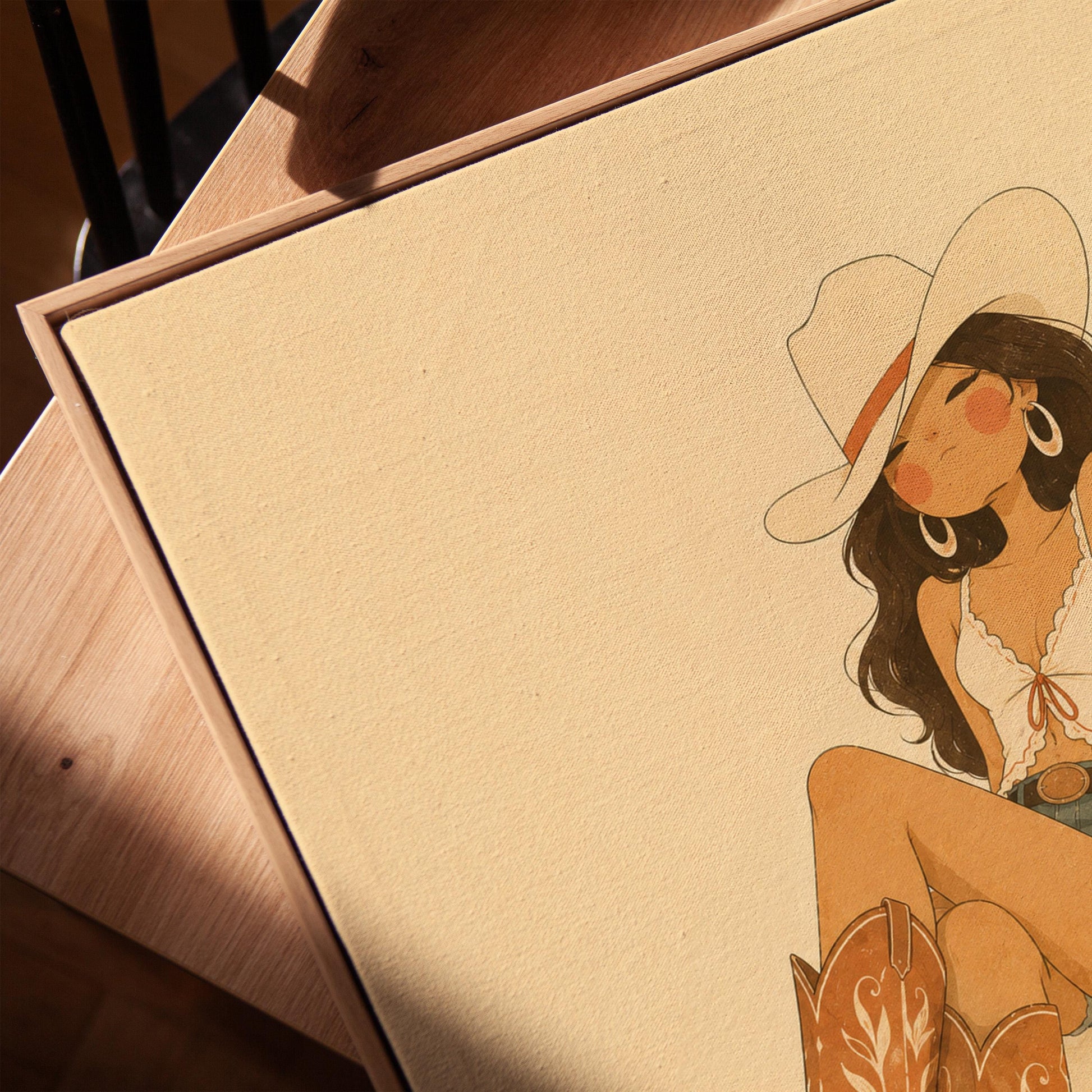 Cowgirl in denim shorts and cowboy boots leaning back under a wide pale hat, canvas print in a warm, minimally styled interior