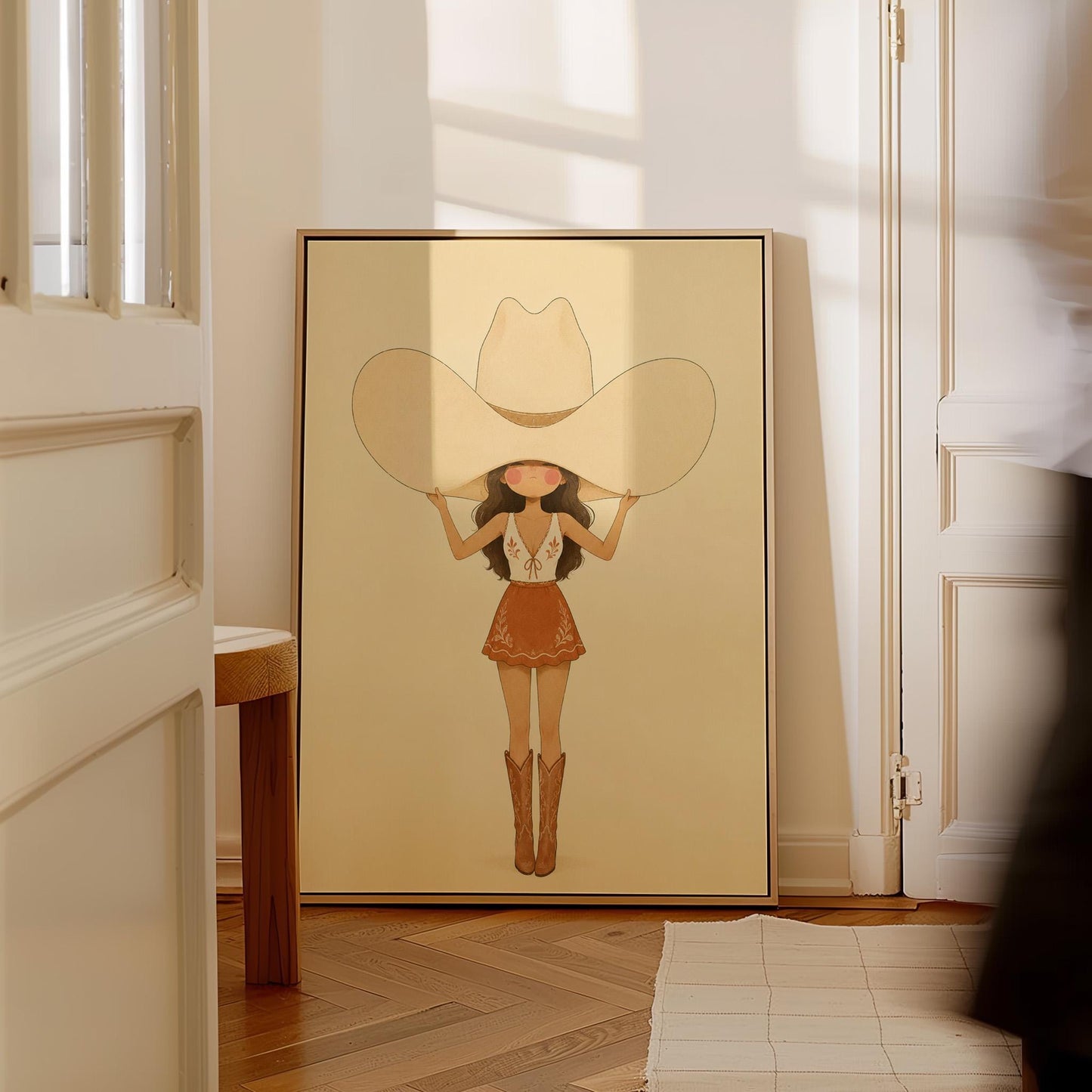 Cowgirl lifting an oversized cream cowboy hat above her head in tall boots, canvas wall art on a quiet wall in a considered interior
