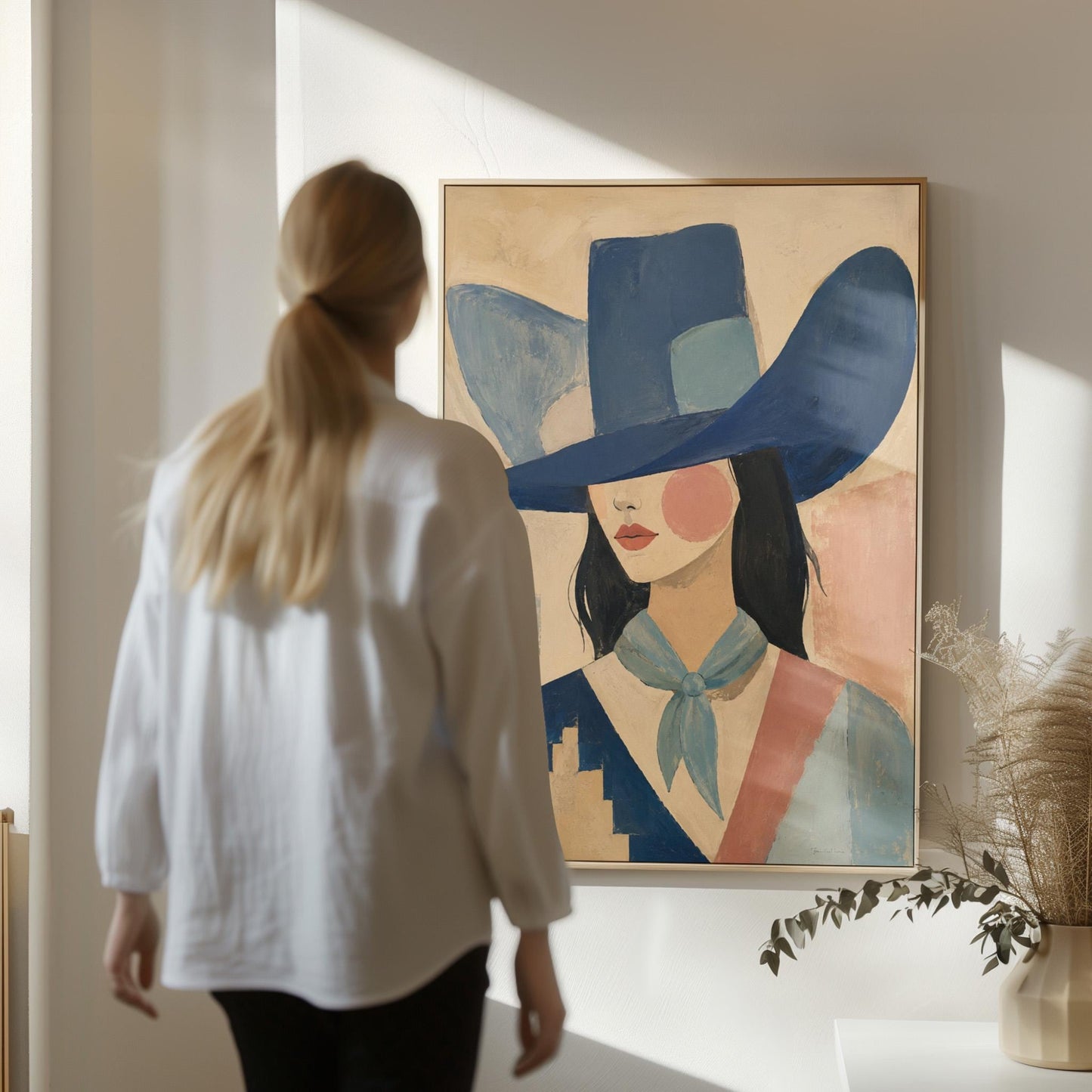 Cowgirl in a deep blue hat and pale scarf on a soft abstract ground, canvas print seen in a warm interior with natural light