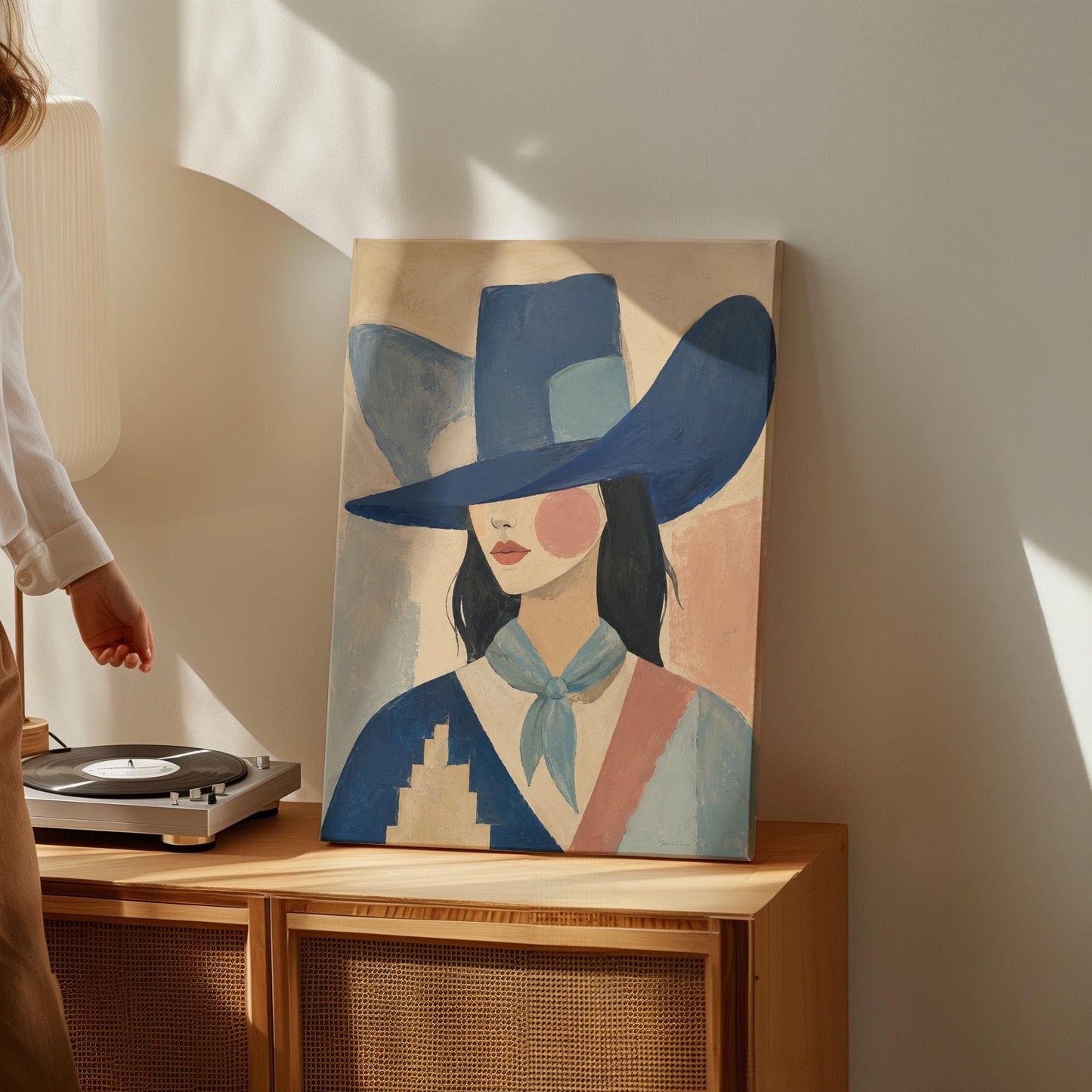 Cowgirl in a deep blue hat and pale scarf on a soft abstract ground, canvas print shown in a sunlit, contemporary room