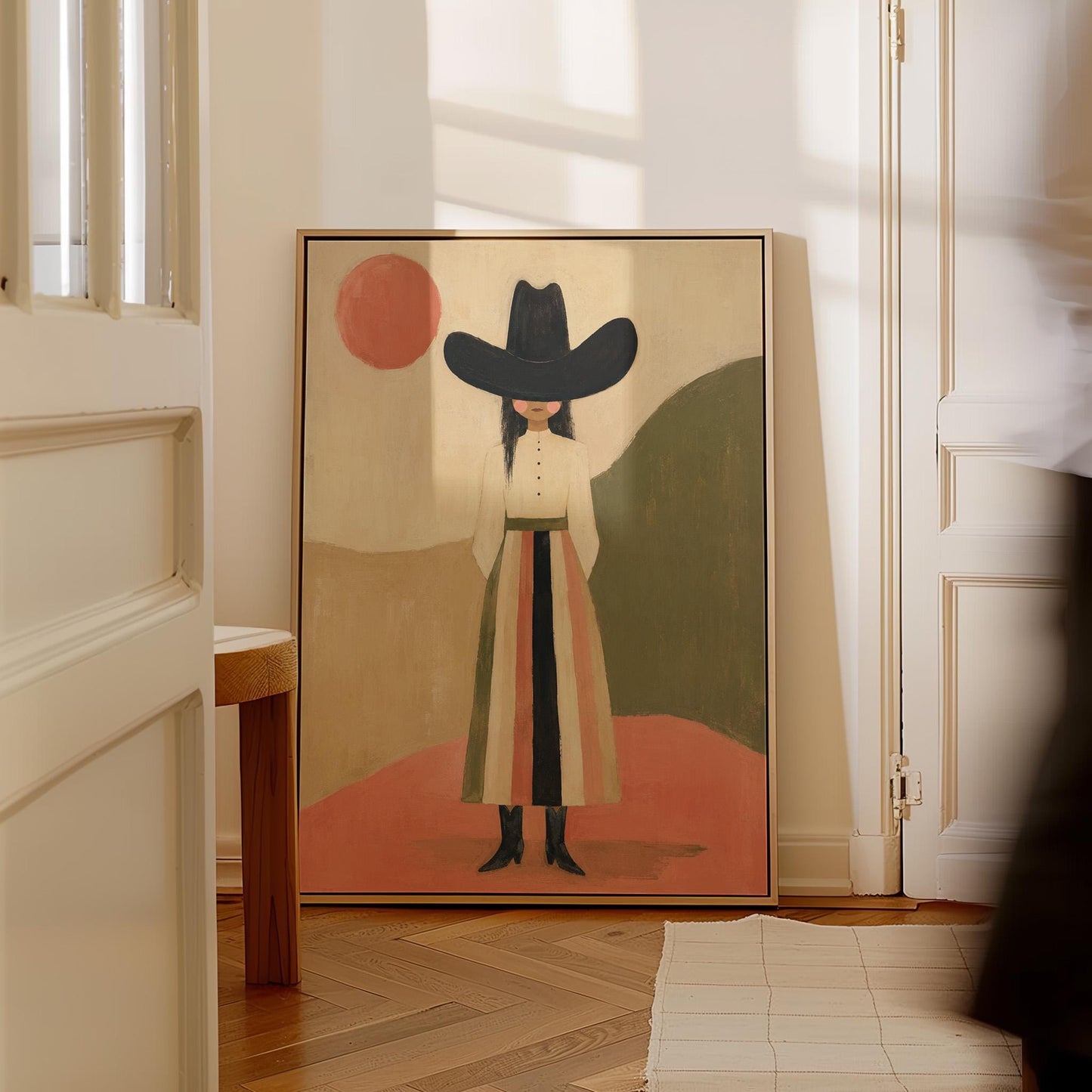 Figure in black cowboy hat standing between coral desert hills, canvas wall art presented in a light, minimal room