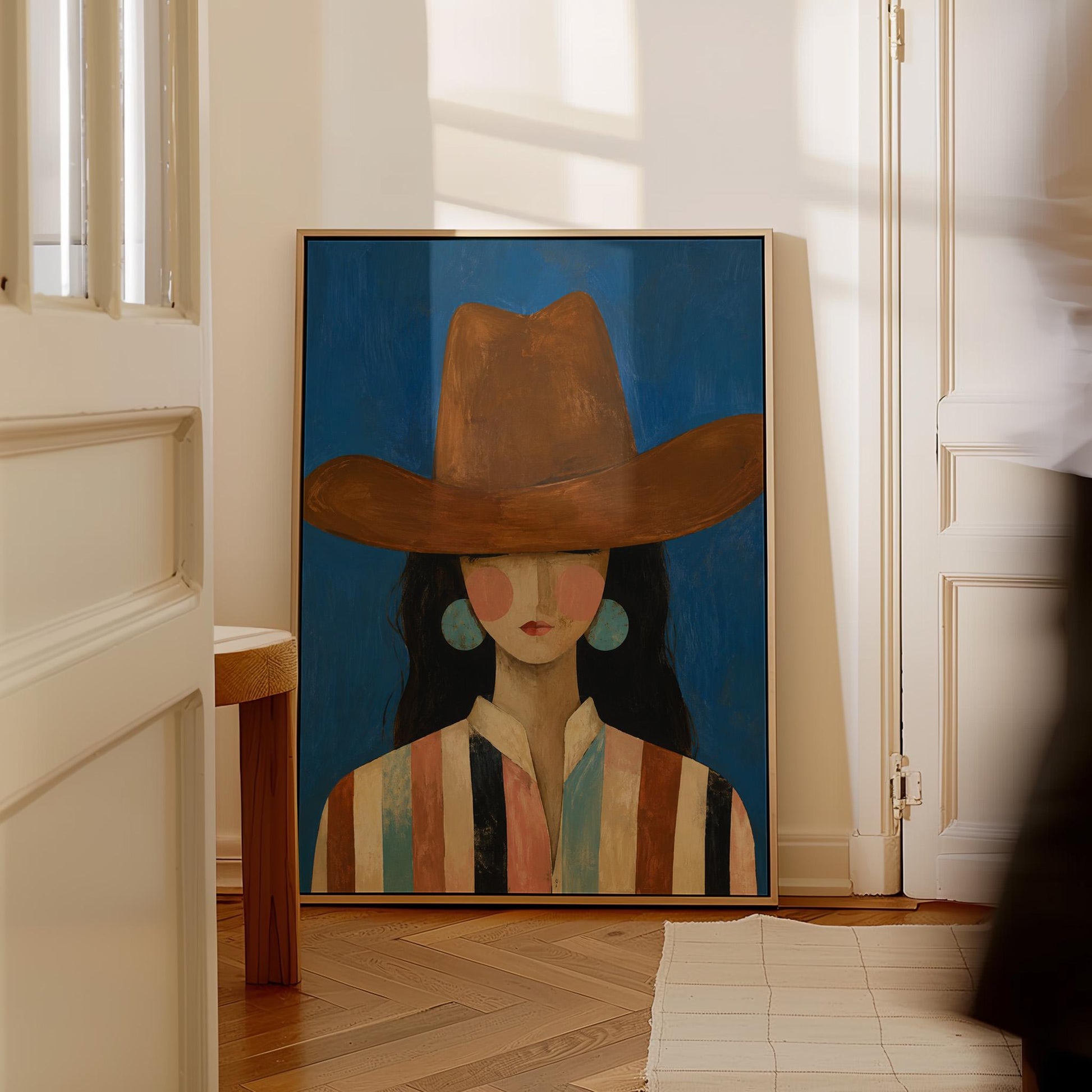 Cowgirl in a brown hat and turquoise earrings on cobalt blue, canvas print presented in a light, minimal room