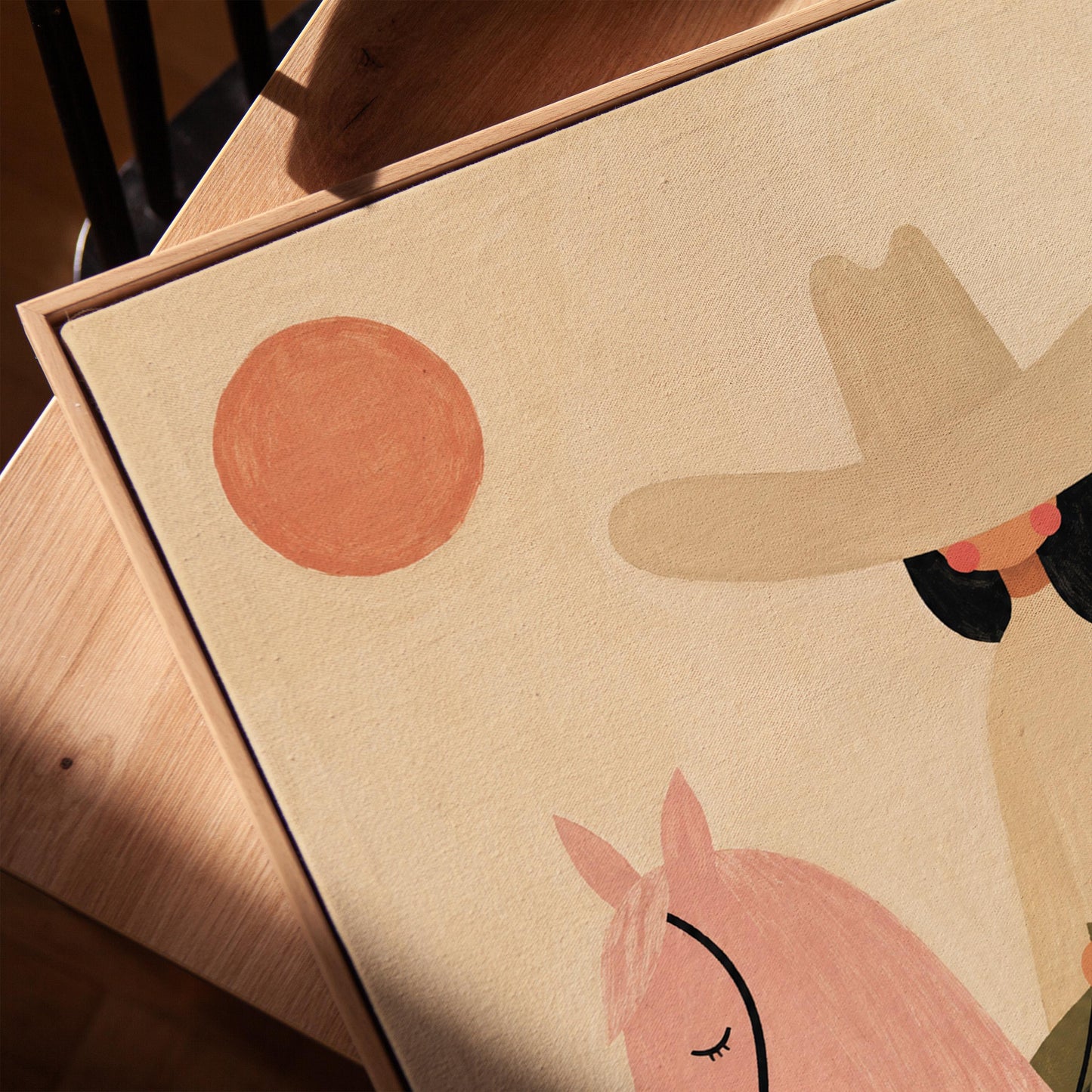 Cowgirl in a pale hat riding a soft pink horse past a desert cactus, canvas print in a warm, minimally styled interior