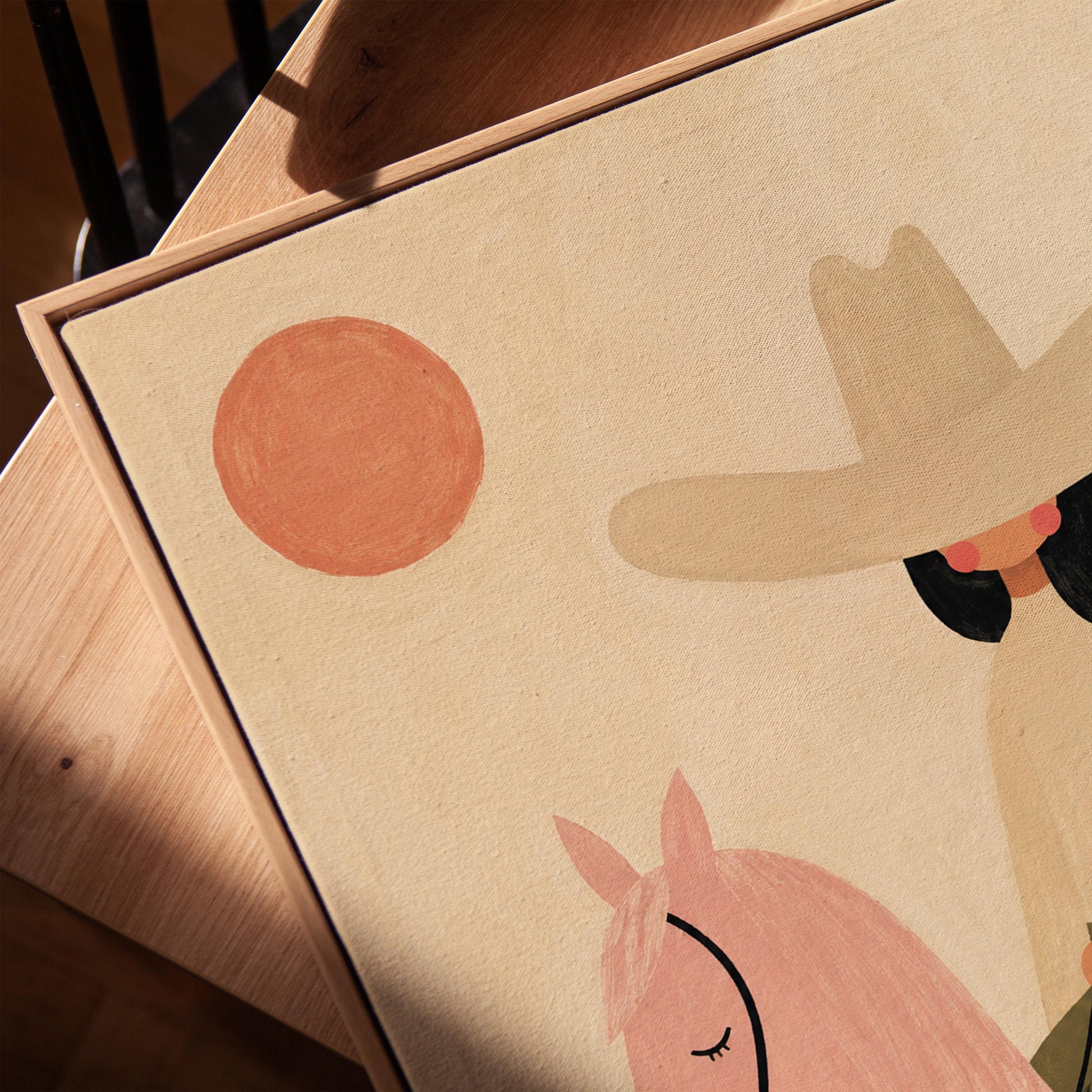 Cowgirl in a pale hat riding a soft pink horse past a desert cactus, canvas print in a warm, minimally styled interior