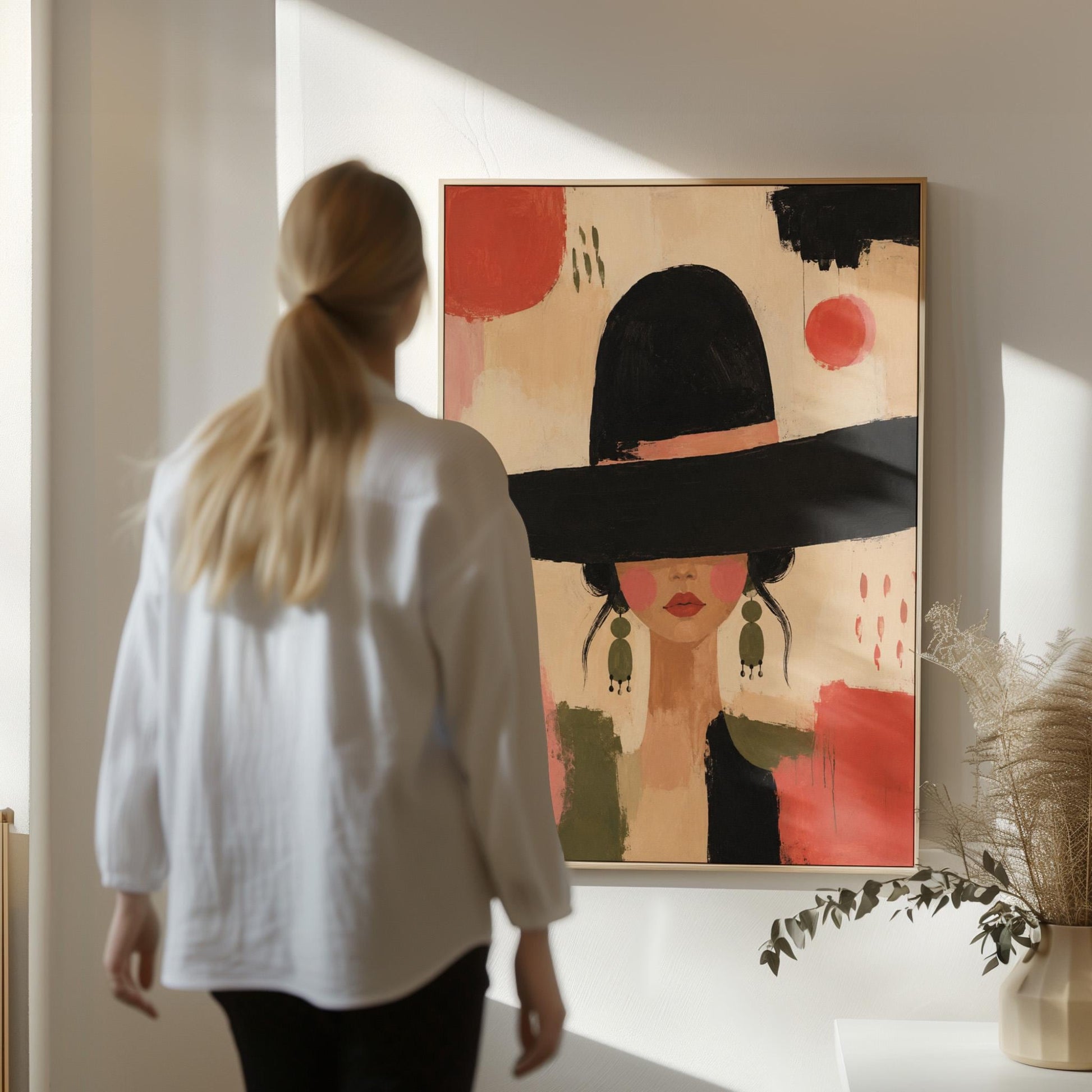Woman in a wide black hat with olive earrings on red brushwork, canvas print shown to scale in a furnished room