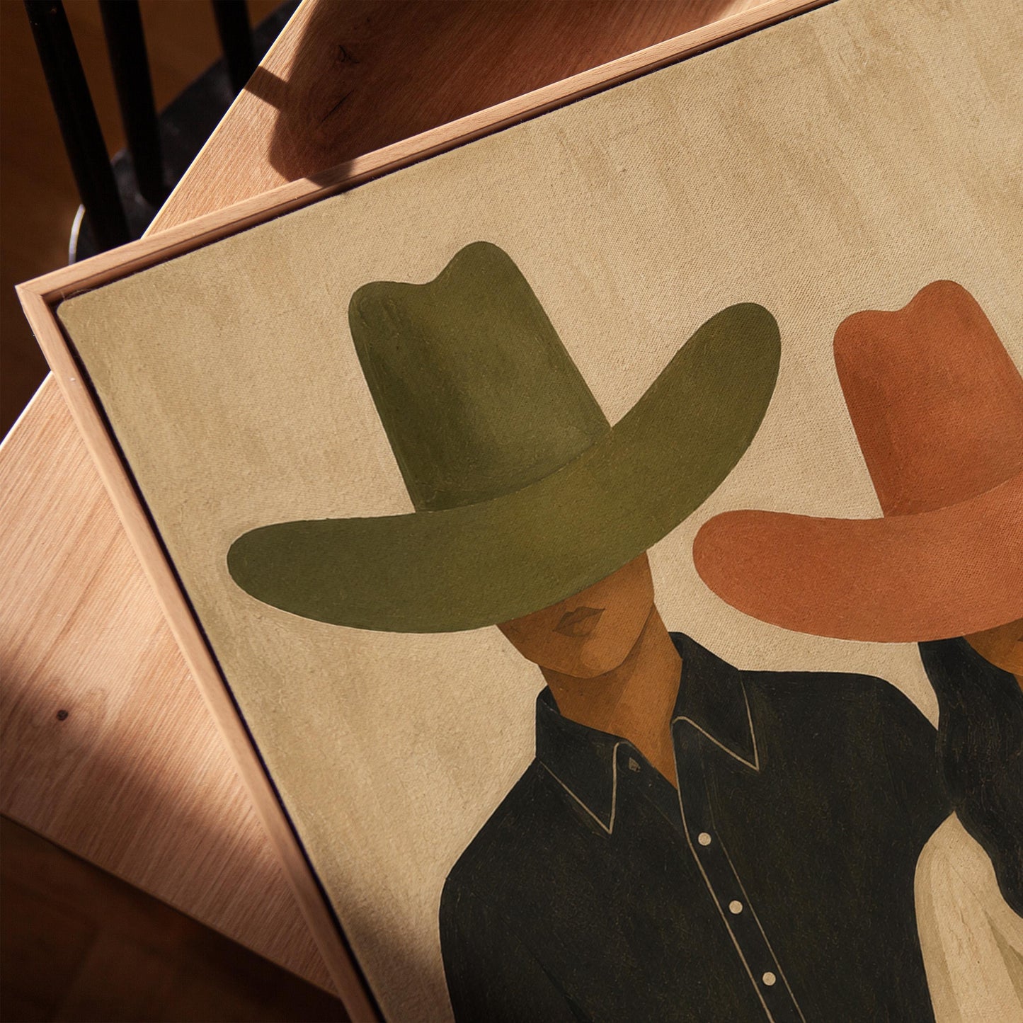 Cowboy and cowgirl standing side by side with hats tipped low, canvas print in a warm, minimally styled interior