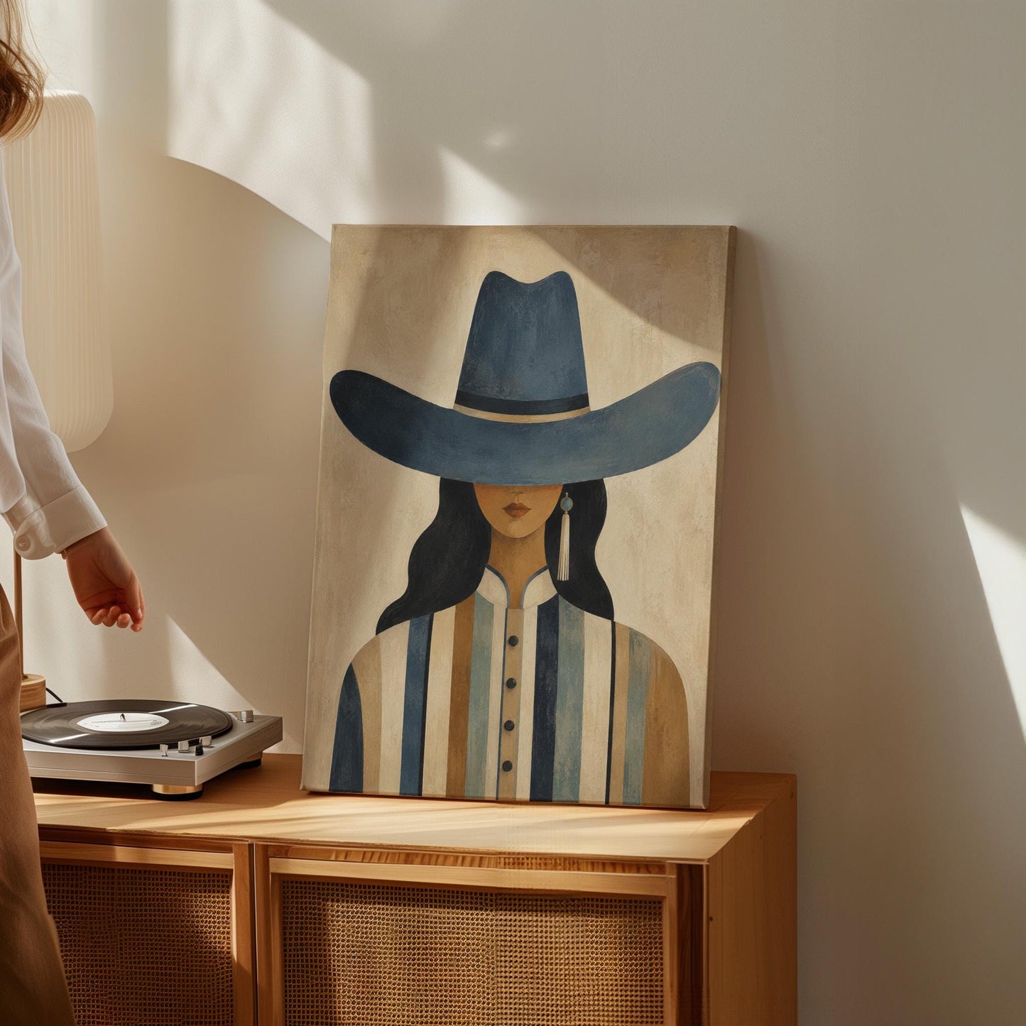 Cowgirl in a slate blue hat and striped shirt on warm sand, canvas print styled against a soft white wall