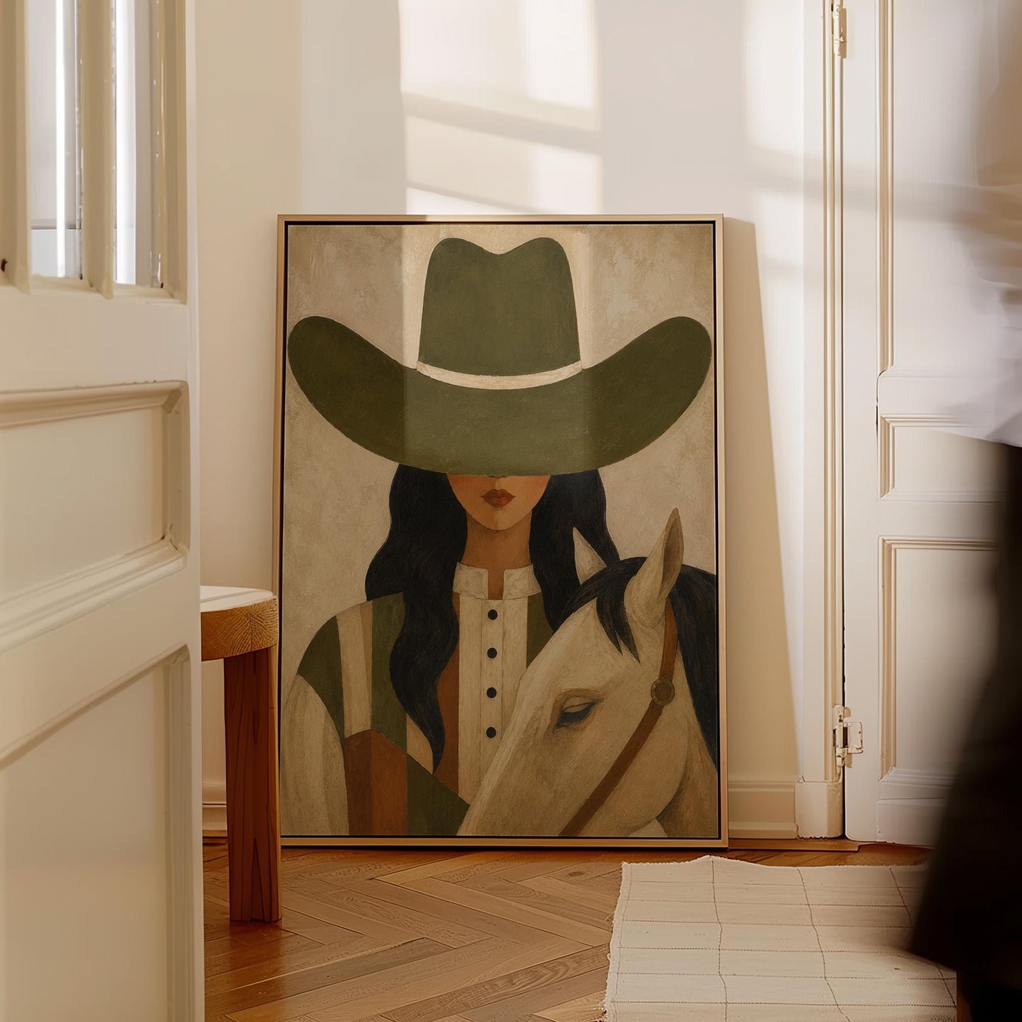 Cowgirl in an olive hat leaning close to a pale white horse, canvas print presented in a light, minimal room