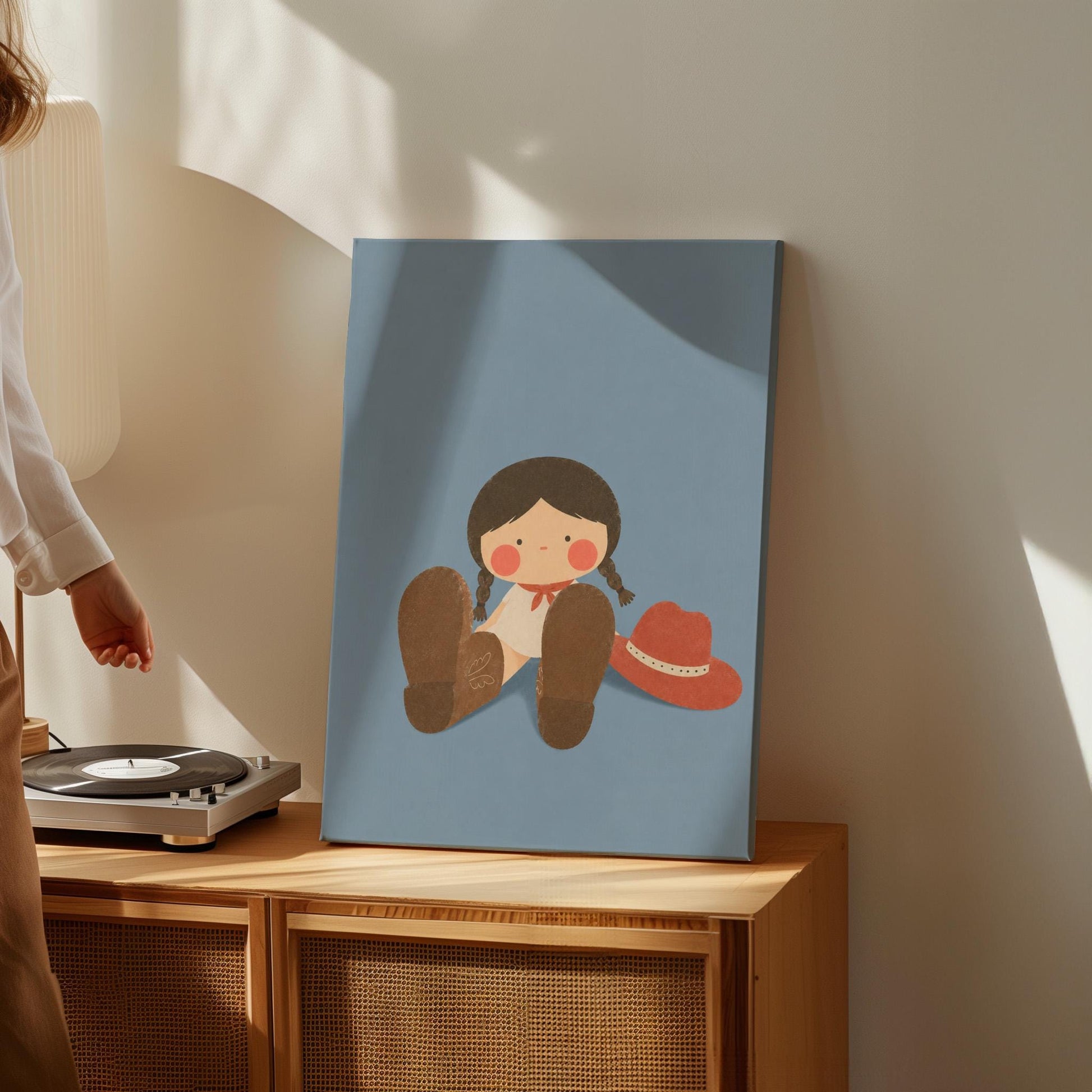 Little cowgirl sitting with big brown boots and a red hat, canvas wall art styled against a soft white wall