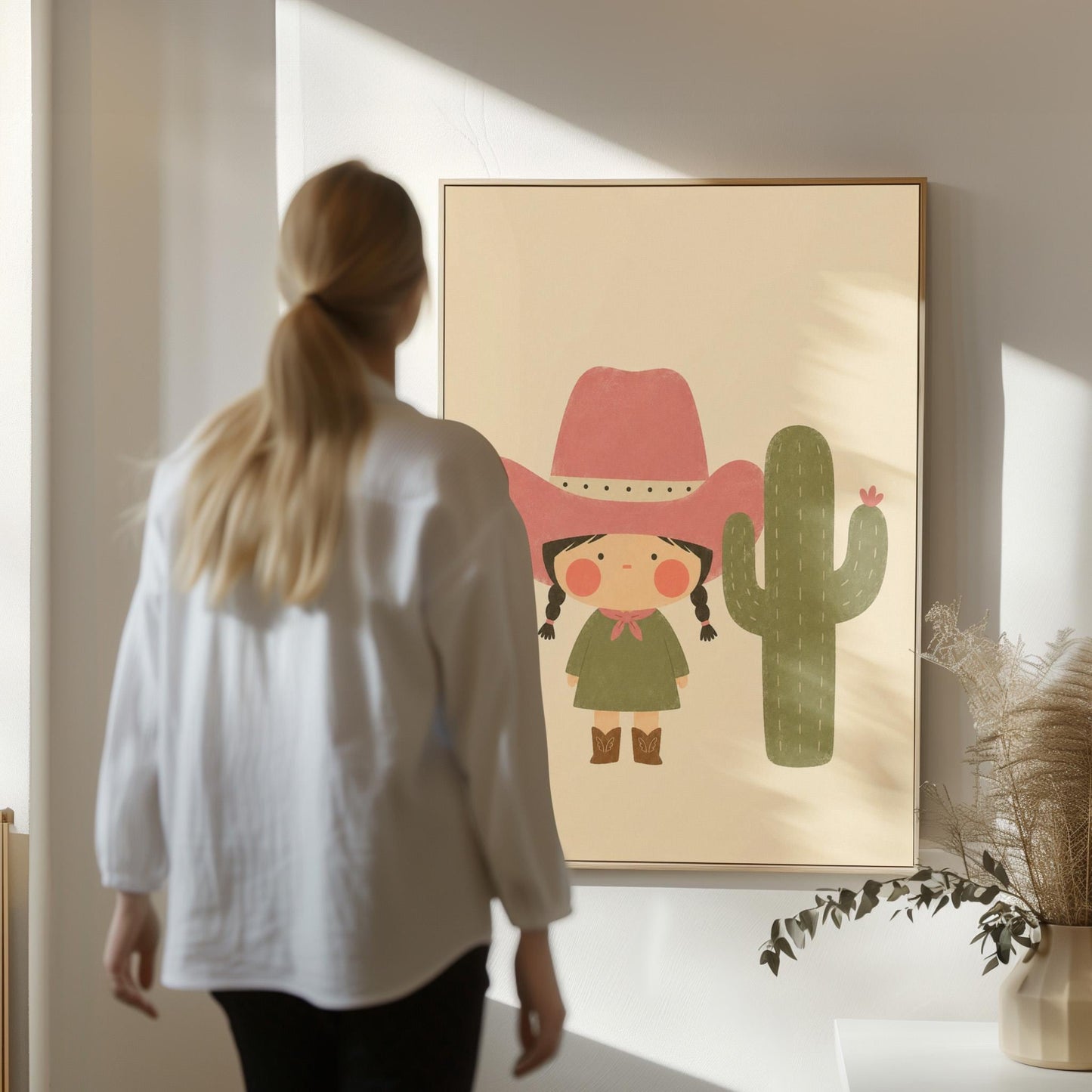 Little cowgirl in a pink hat next to a tall flowering cactus, canvas print displayed on a neutral wall in a styled interior