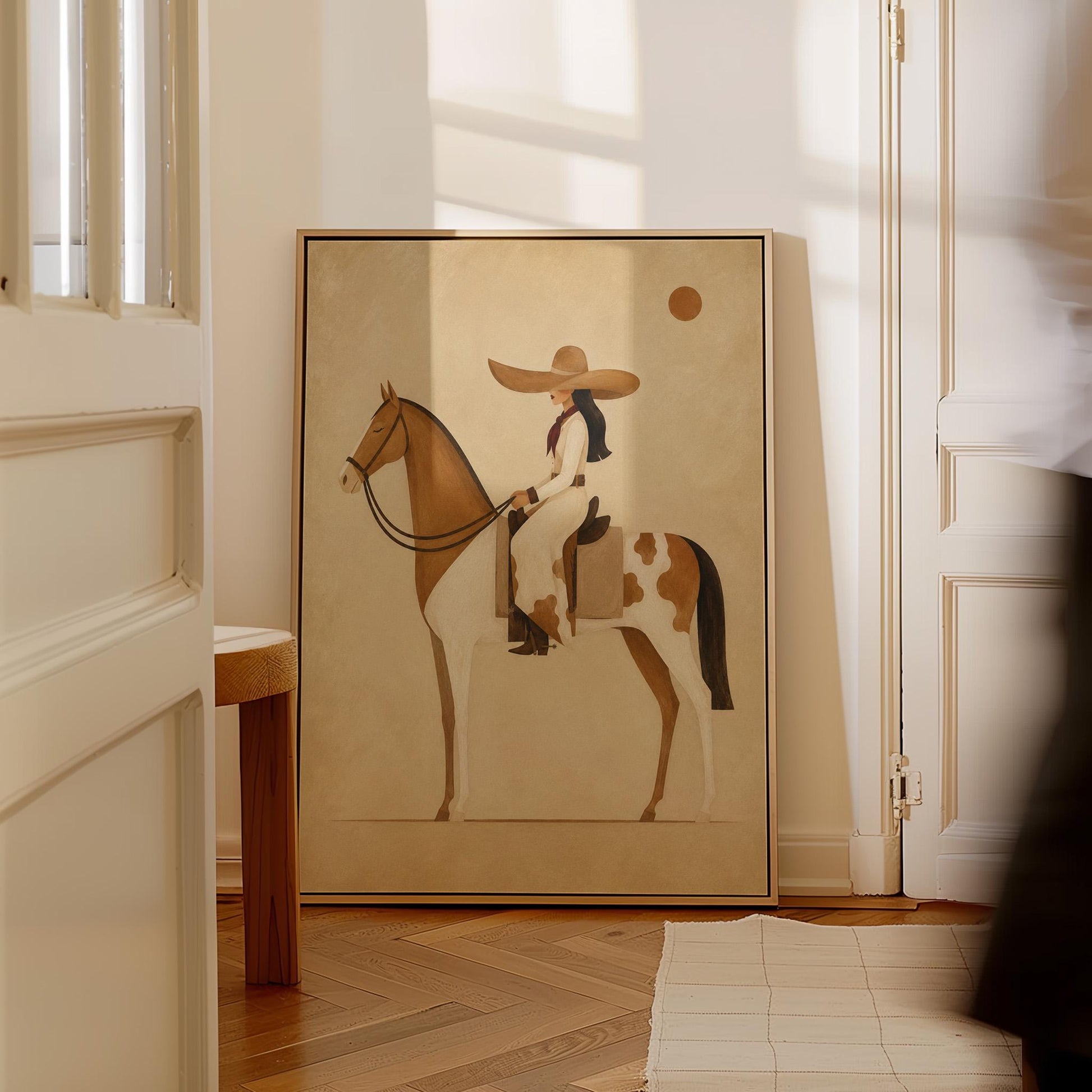 Cowgirl in a broad straw hat riding a cream and chestnut pinto horse, canvas wall art presented in a light, minimal room