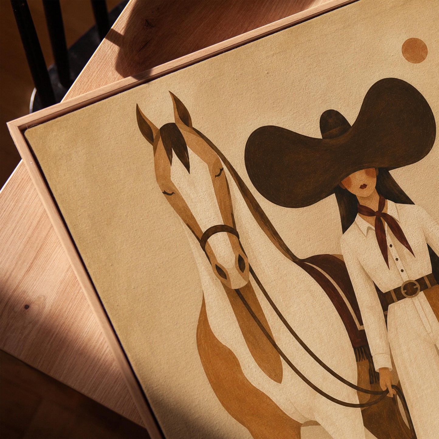 Cowgirl in a sculptural black hat standing with a horse in the desert sun, canvas print in a warm, minimally styled interior