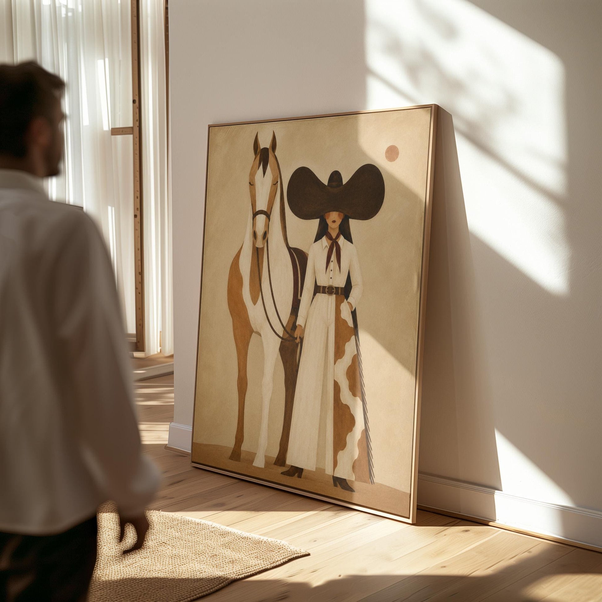Cowgirl in a sculptural black hat standing with a horse in the desert sun, canvas print seen in a warm interior with natural light