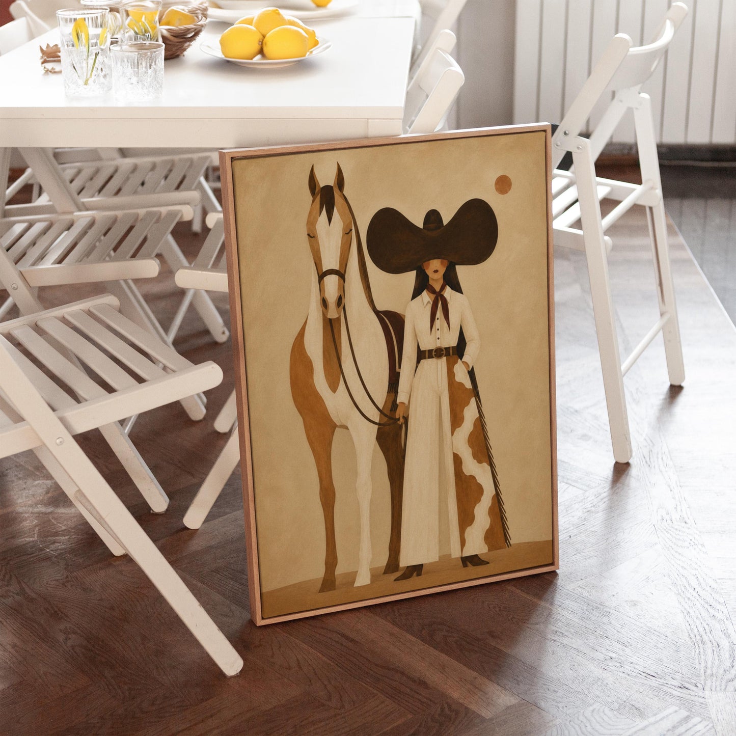 Cowgirl in a sculptural black hat standing with a horse in the desert sun, canvas print shown to scale in a furnished room