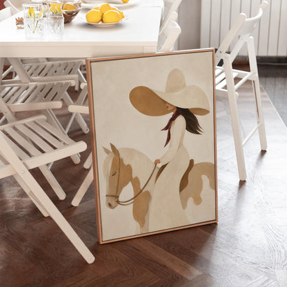 Woman in a long white dress and floppy hat riding a spotted horse, canvas print shown to scale in a furnished room