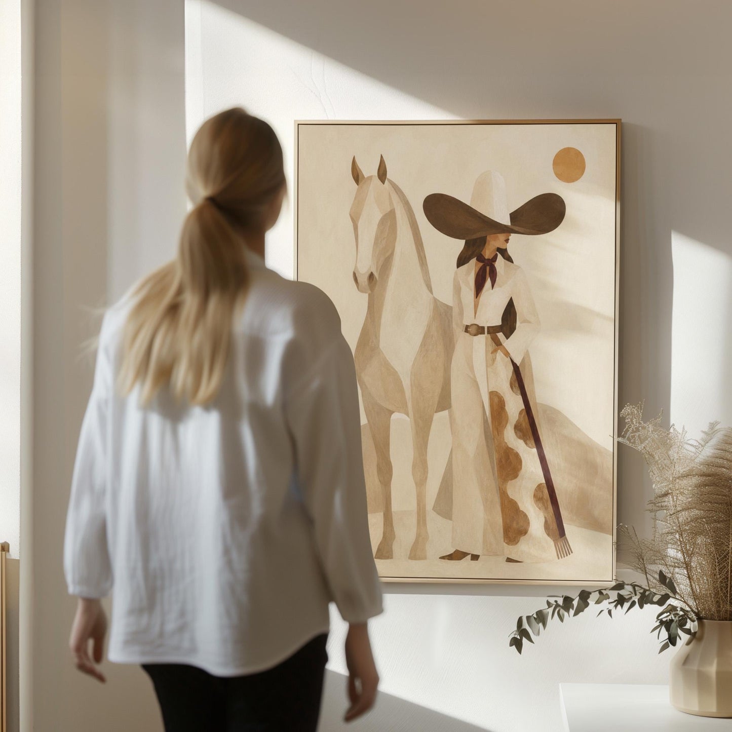 Cowgirl in a dark hat with a pale horse before soft desert hills, canvas print on a quiet wall in a considered interior