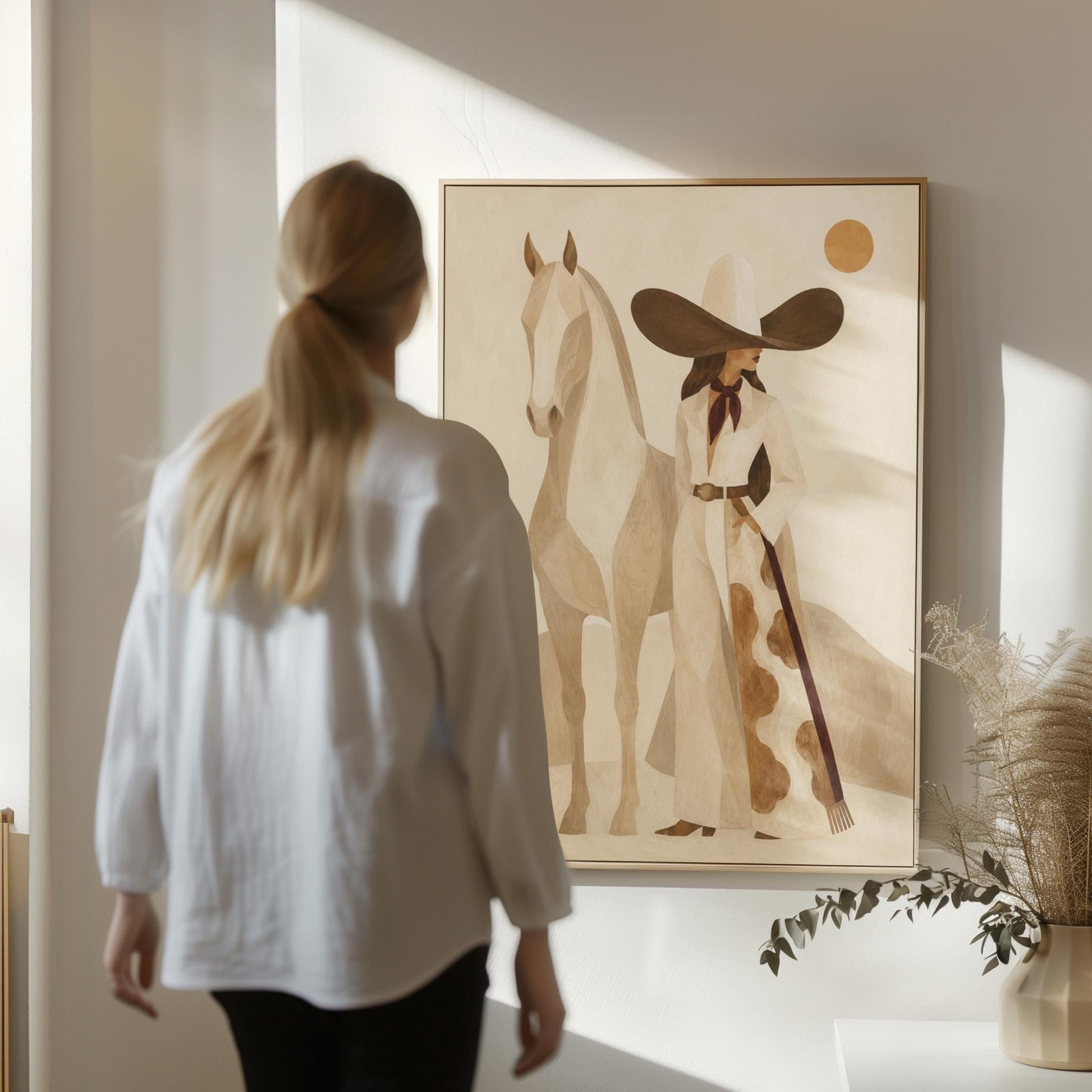 Cowgirl in a dark hat with a pale horse before soft desert hills, canvas print on a quiet wall in a considered interior