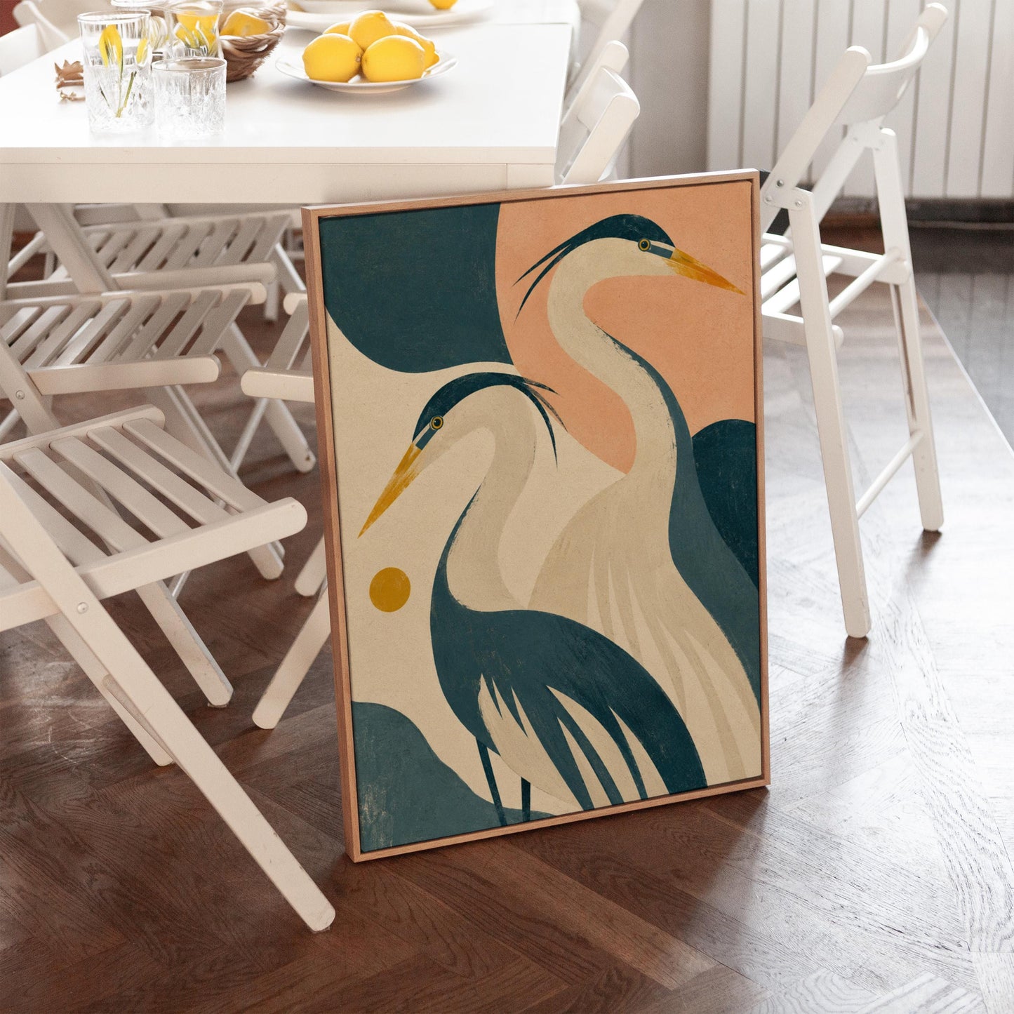 Two great herons with yellow beaks against a peach and teal sky, canvas print shown to scale in a furnished room