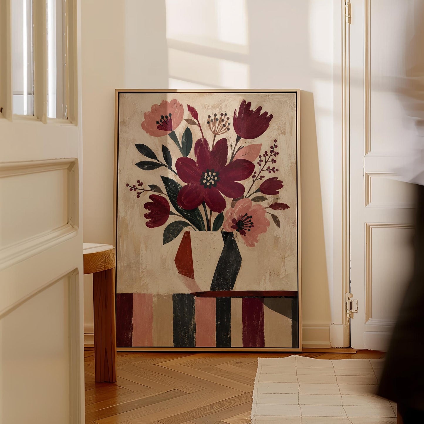Burgundy and dusty pink flowers in a striped vase on a striped table, canvas print displayed on a neutral wall in a styled interior