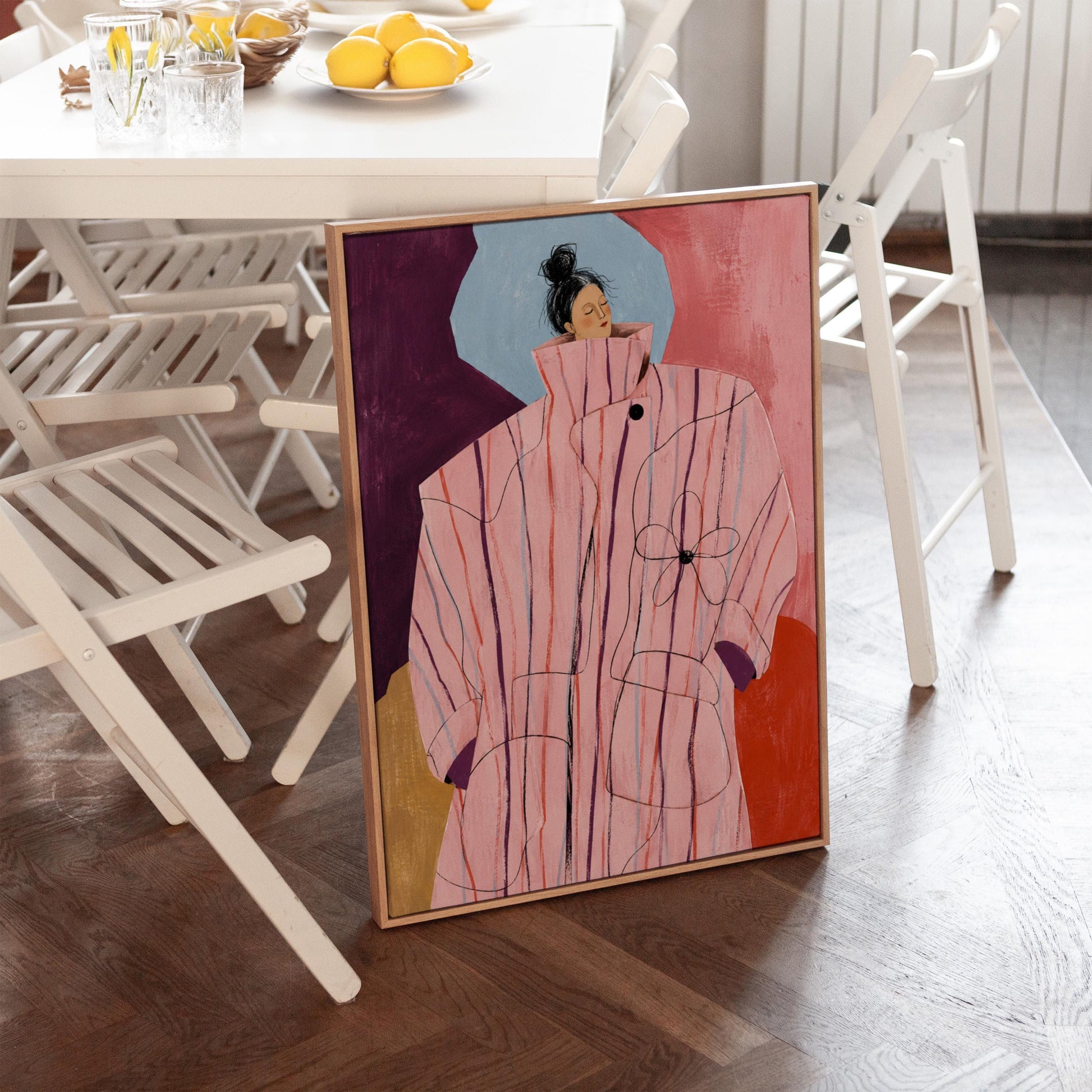Woman in an oversized pink striped coat against plum and coral blocks, canvas print shown to scale in a furnished room