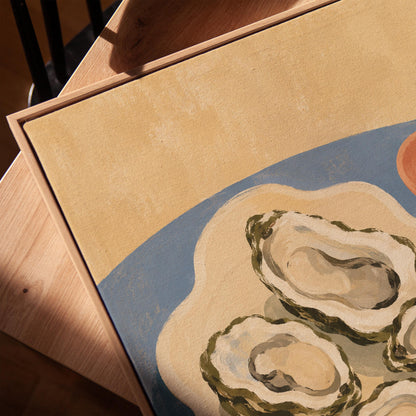 Four open oysters on a cream platter with lemon on a dusty blue ground, canvas print in a warm, minimally styled interior