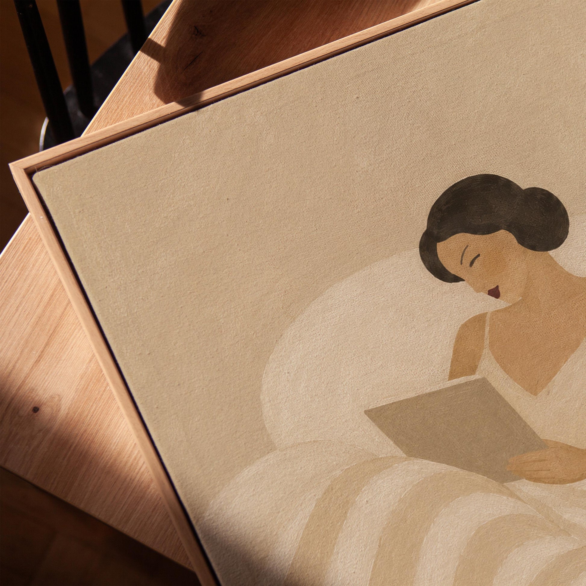 Woman in a white slip sitting up in bed reading in morning light, canvas print in a warm, minimally styled interior