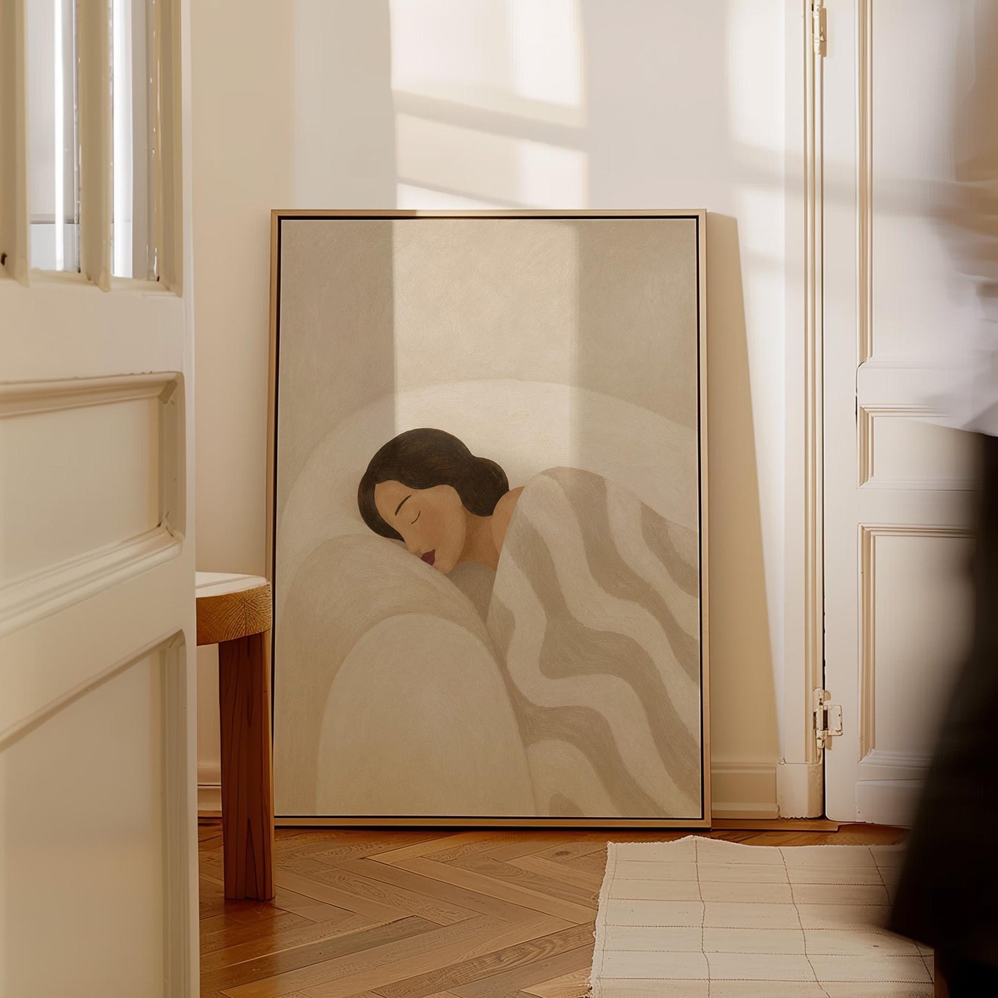 Woman asleep beneath a quilt of rolling cream and sand wave shapes, canvas wall art styled against a soft white wall