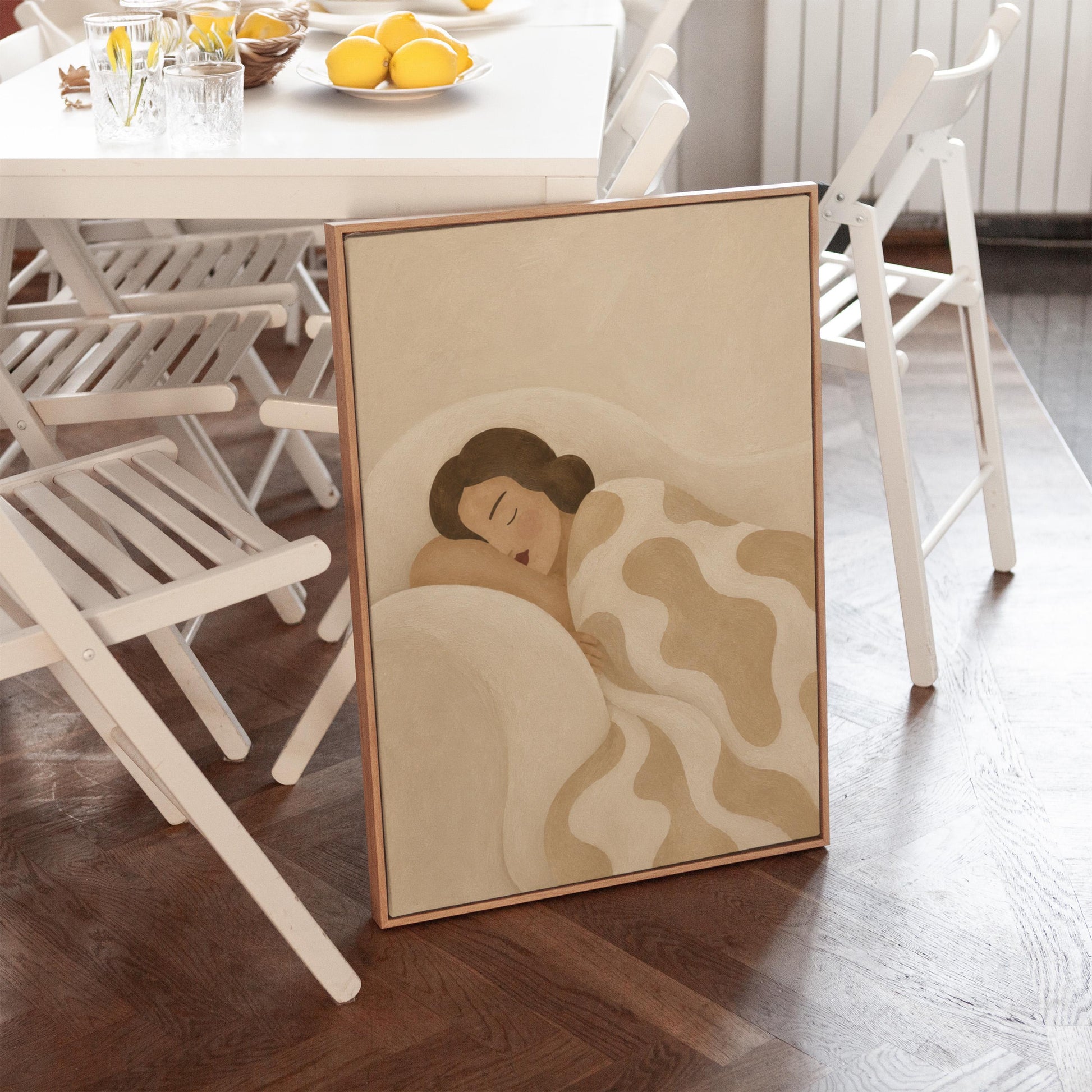 Woman sleeping under a cream blanket with soft camel cloud shapes, canvas print seen in a warm interior with natural light