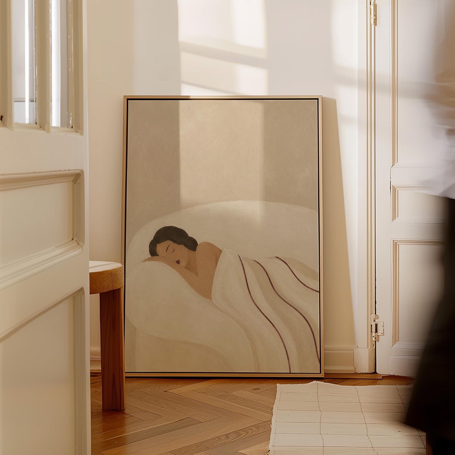 Woman asleep on her side under white linen with thin maroon lines, canvas print presented in a light, minimal room