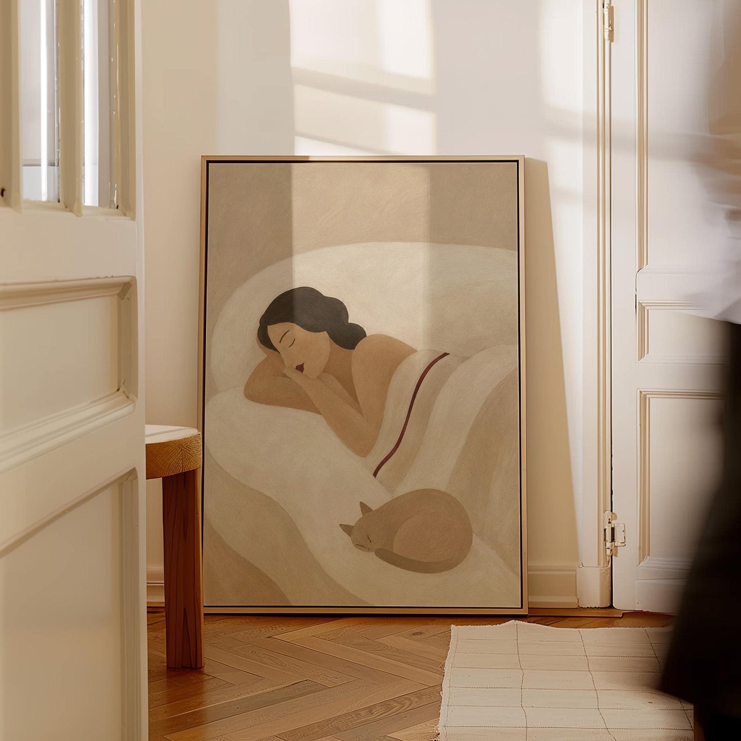 Woman sleeping with a small white cat curled at the foot of the bed, canvas print hanging in a calm, modern living space