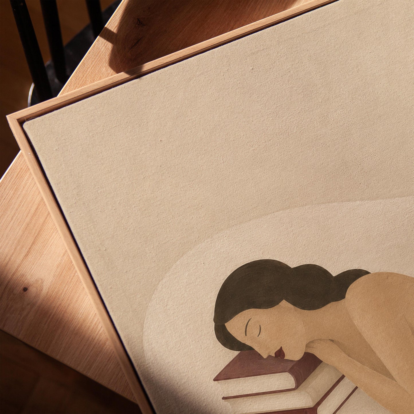 Woman resting her cheek on a stack of cream and burgundy books, canvas print in a warm, minimally styled interior