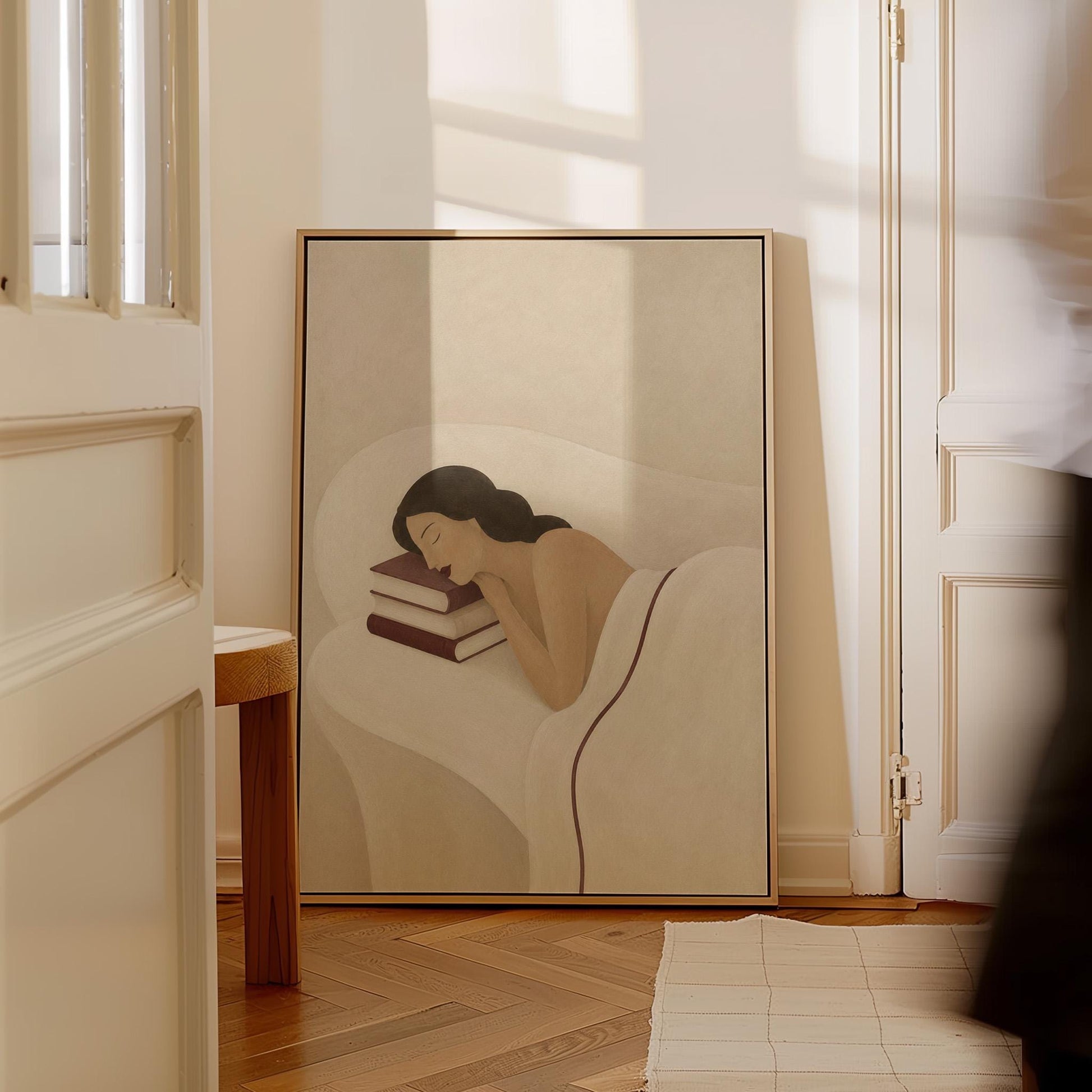 Woman resting her cheek on a stack of cream and burgundy books, canvas print on a quiet wall in a considered interior