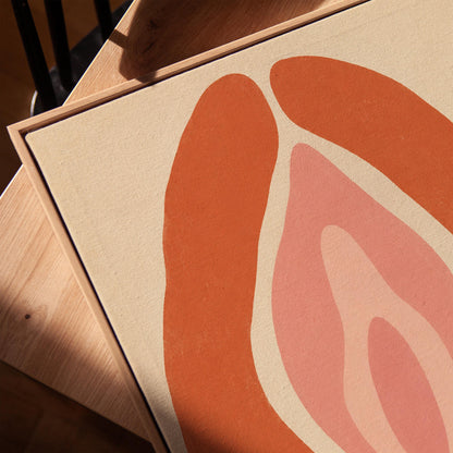 Rust orange arcs curving around a nested blush pink core on sand, canvas print in a warm, minimally styled interior