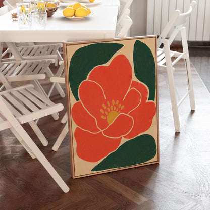 Scarlet flower with gold stamens over deep green leaves on sand, canvas print presented in a light, minimal room