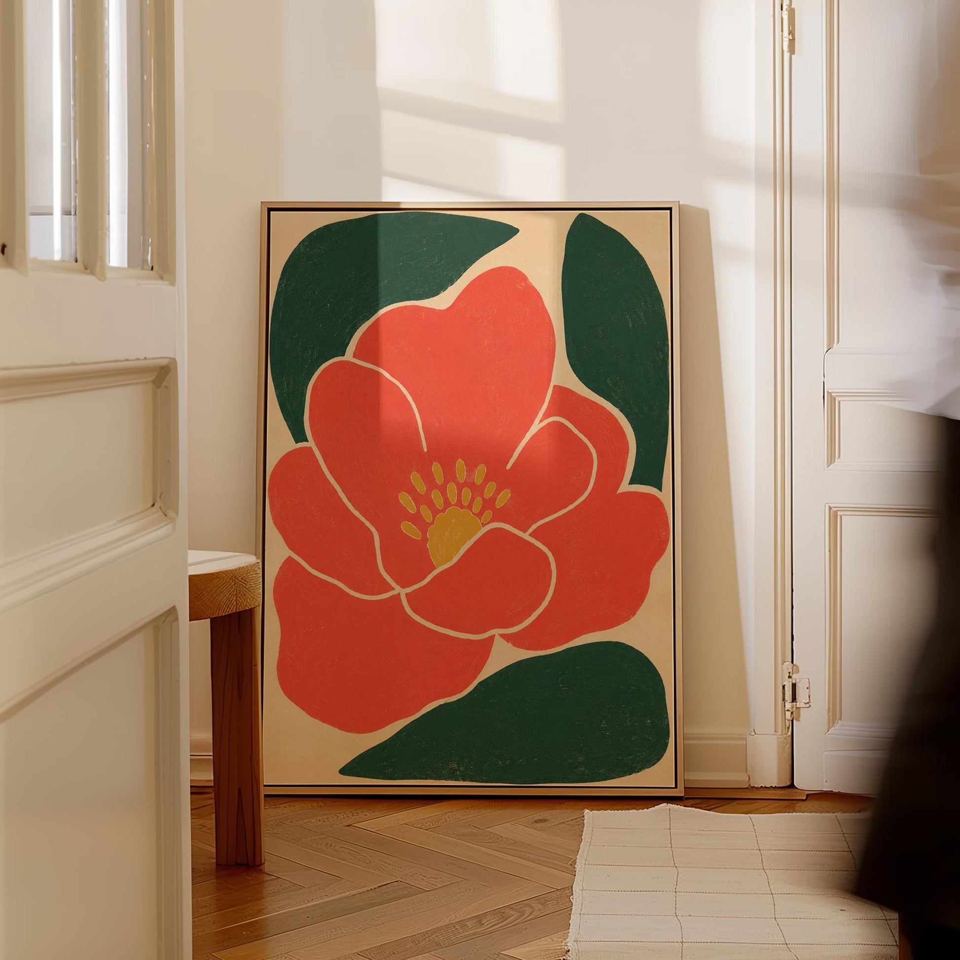 Scarlet flower with gold stamens over deep green leaves on sand, canvas wall art seen in a warm interior with natural light