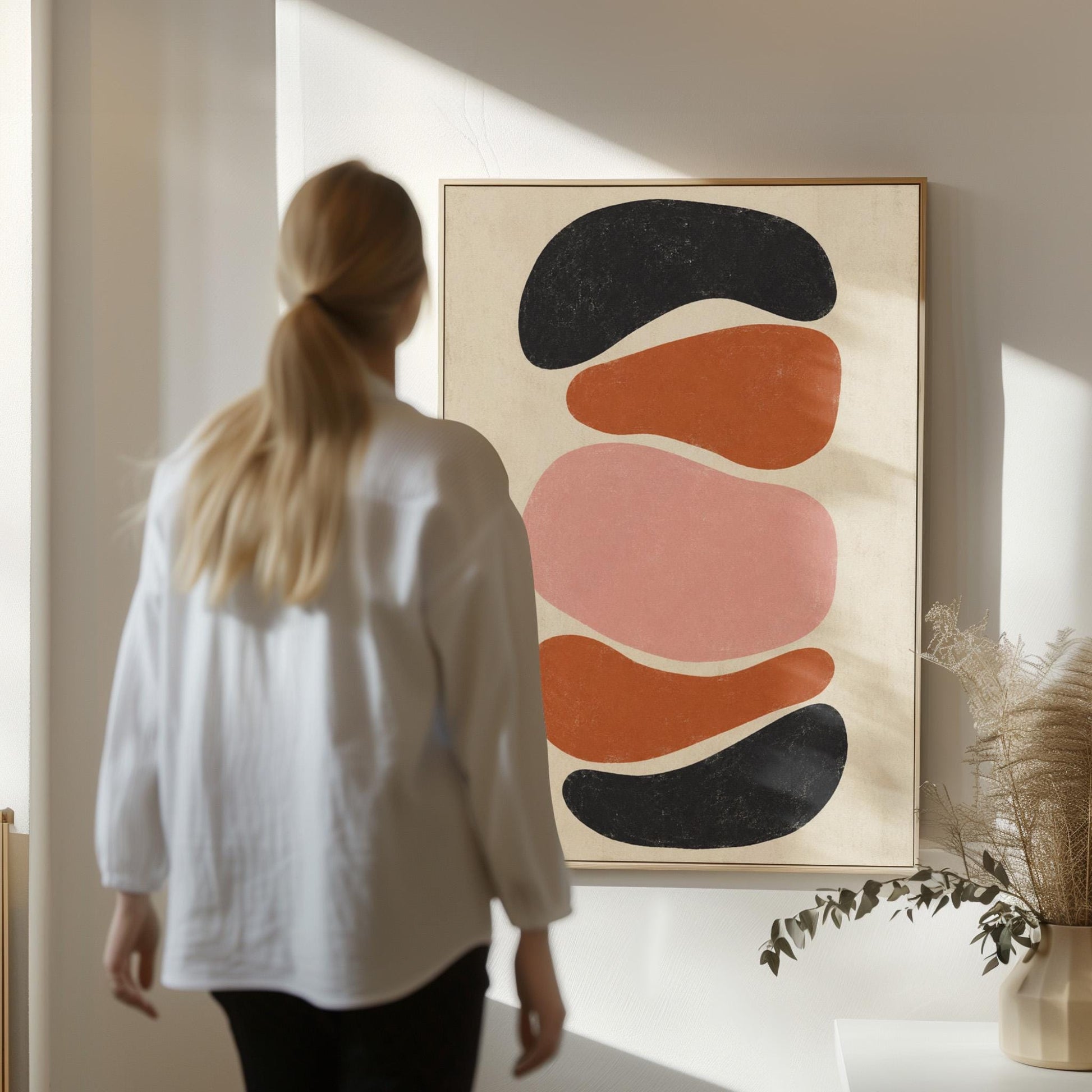 Five stacked pebble shapes in charcoal rust and blush on cream, canvas print styled against a soft white wall