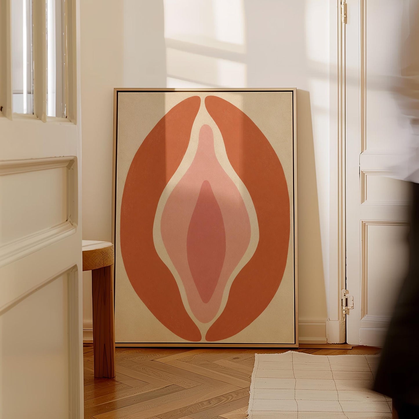 Tall terracotta oval enclosing soft layers of blush and pale rose, canvas print hanging in a calm, modern living space