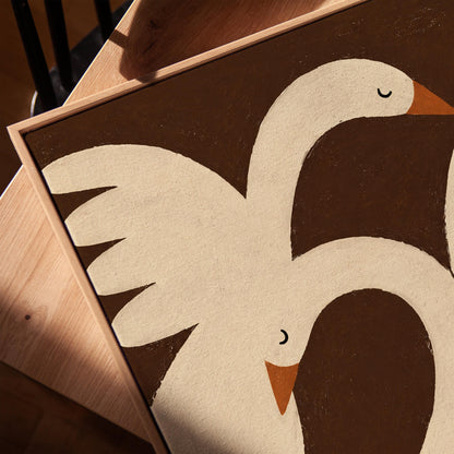 Two cream doves with orange beaks crossing wings on dark brown, canvas print in a warm, minimally styled interior