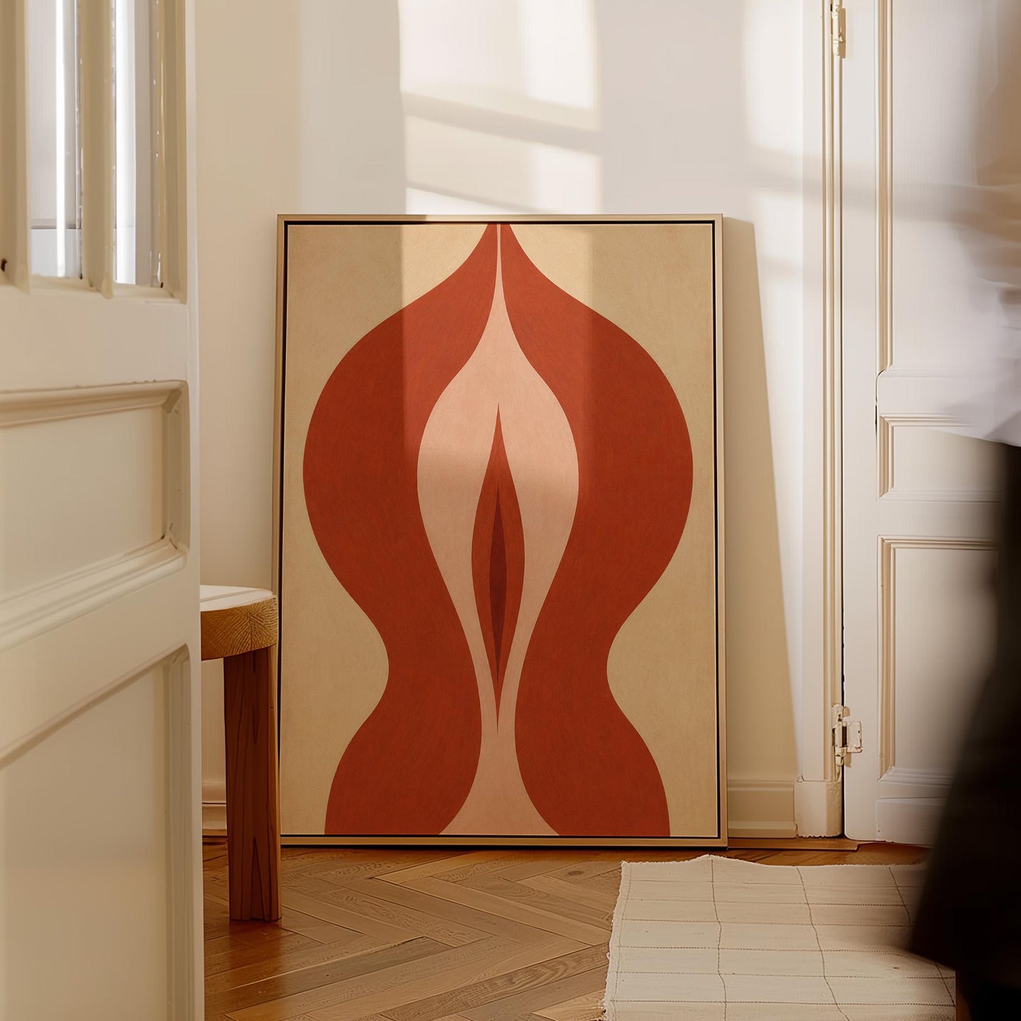 Rust red flame shaped form opening into blush and grey on sand, canvas wall art seen in a warm interior with natural light