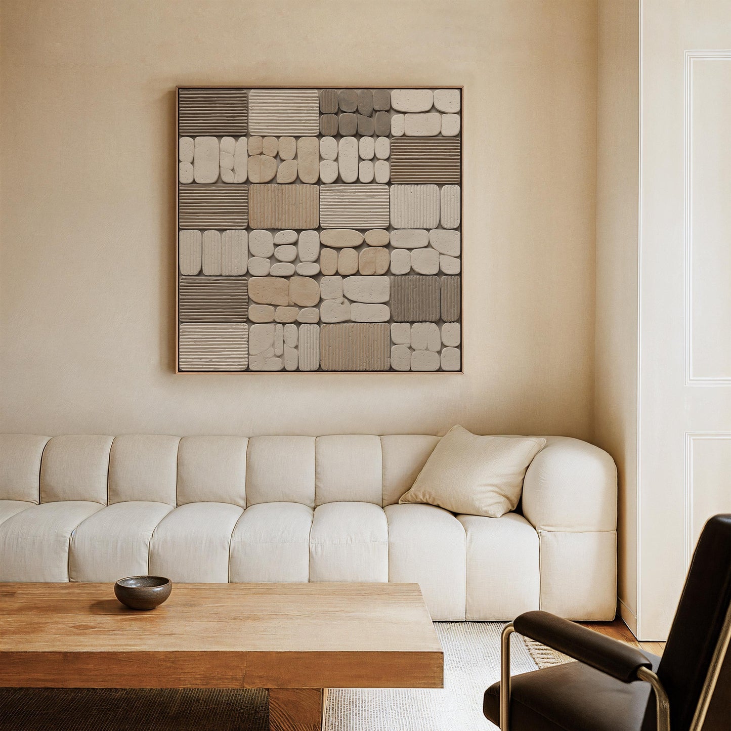 a modern living room with a large abstract artwork hanging on the wall above a white sofa. The sofa is positioned in front of a wooden coffee table, and a black leather chair is situated in the corner of the room.